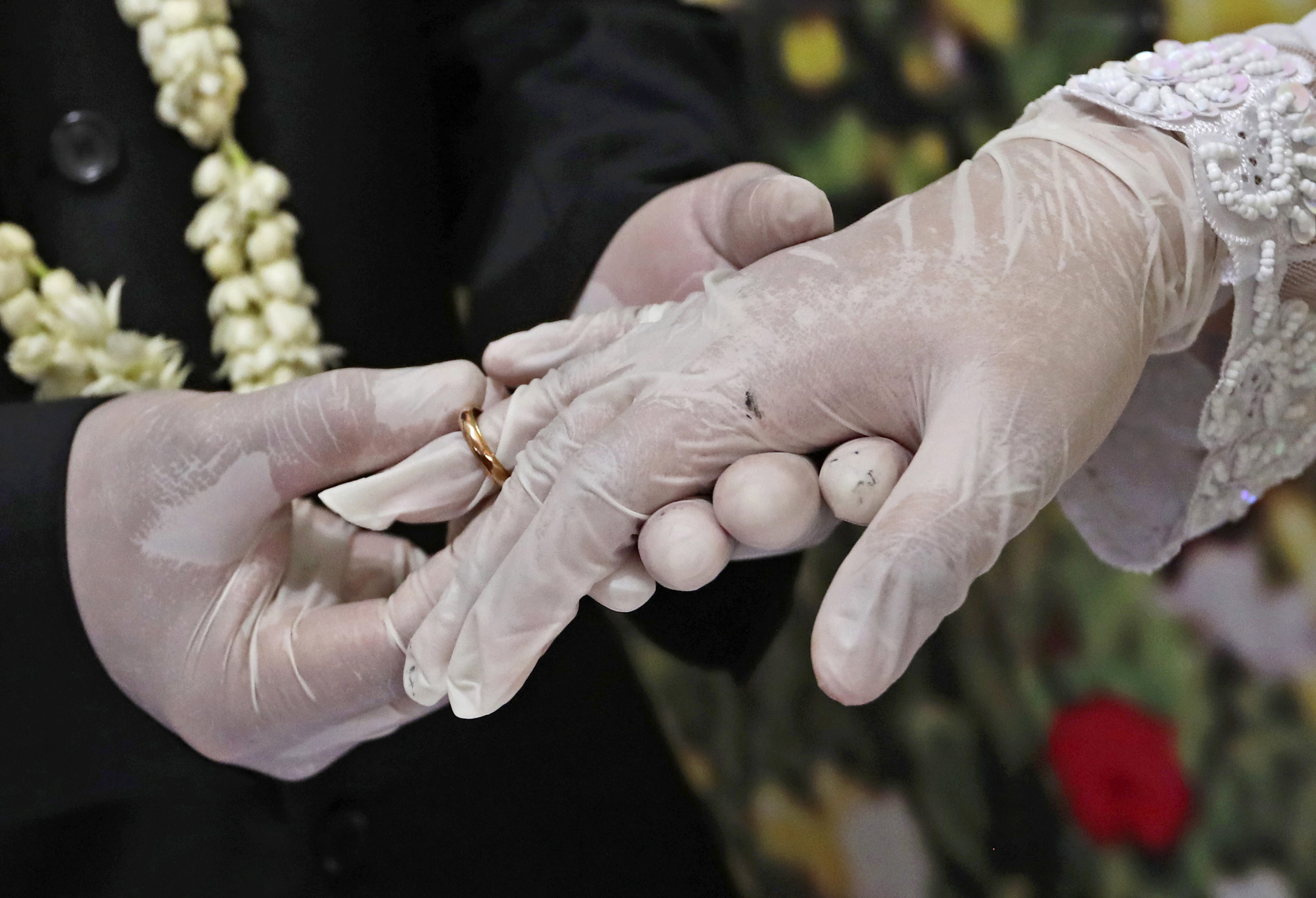 Wearing latex gloves to prevent the spread of the coronavirus, a bride and groom exchange rings during their wedding ceremony in Pamulang, Indonesia. Photo: AP