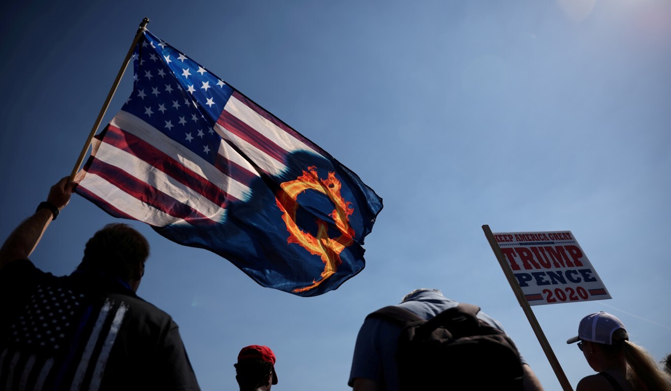 A Trump supporter holds up a US flag with a reference to QAnon during a rally last year. Photo: Reuters
