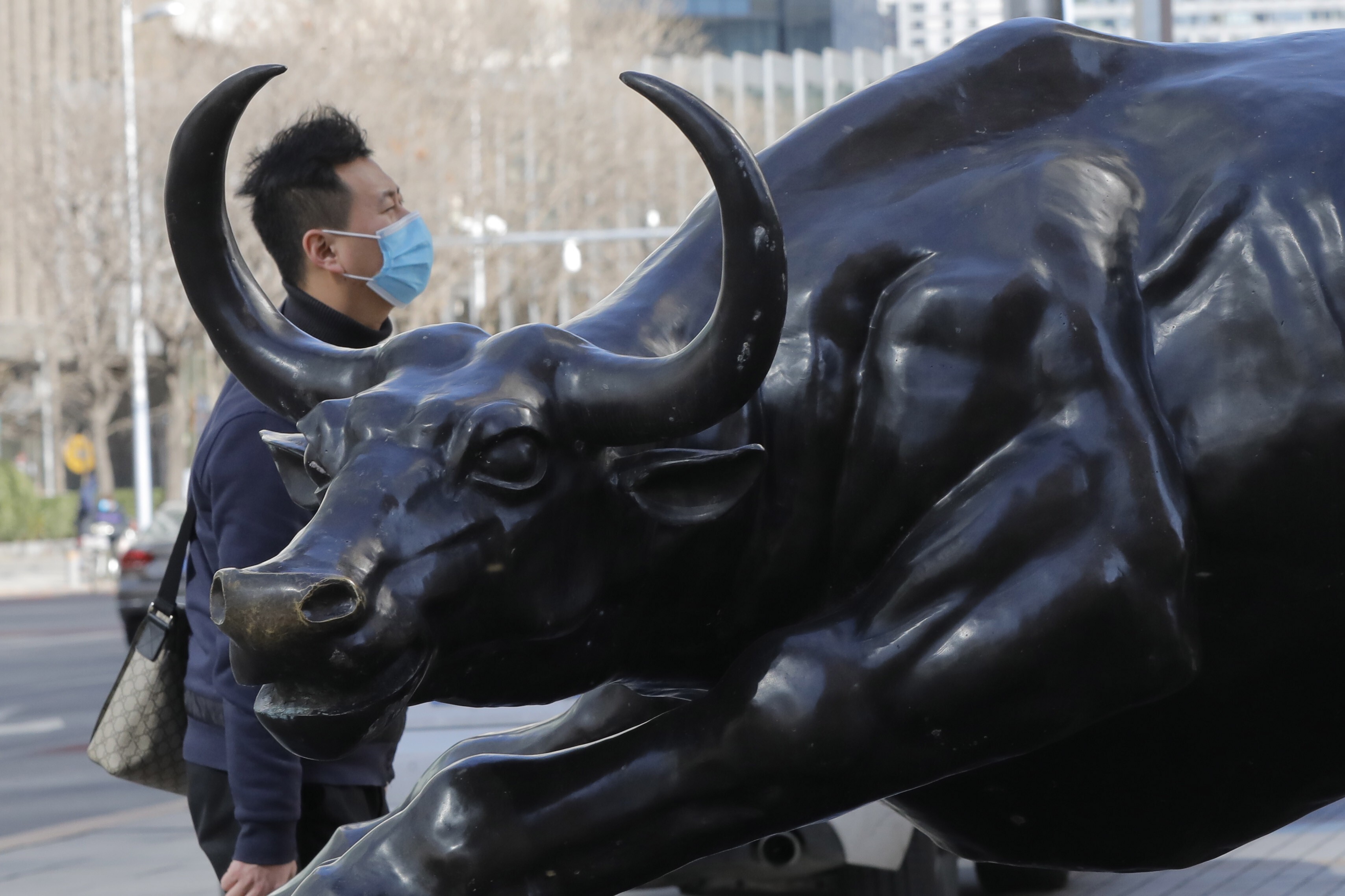 A man walks by a bronze sculpture of a bull in Beijing’s central business district on March 14, 2020. The MSCI China A Onshore Index is trading above its historical average. Photo. EPA-EFE