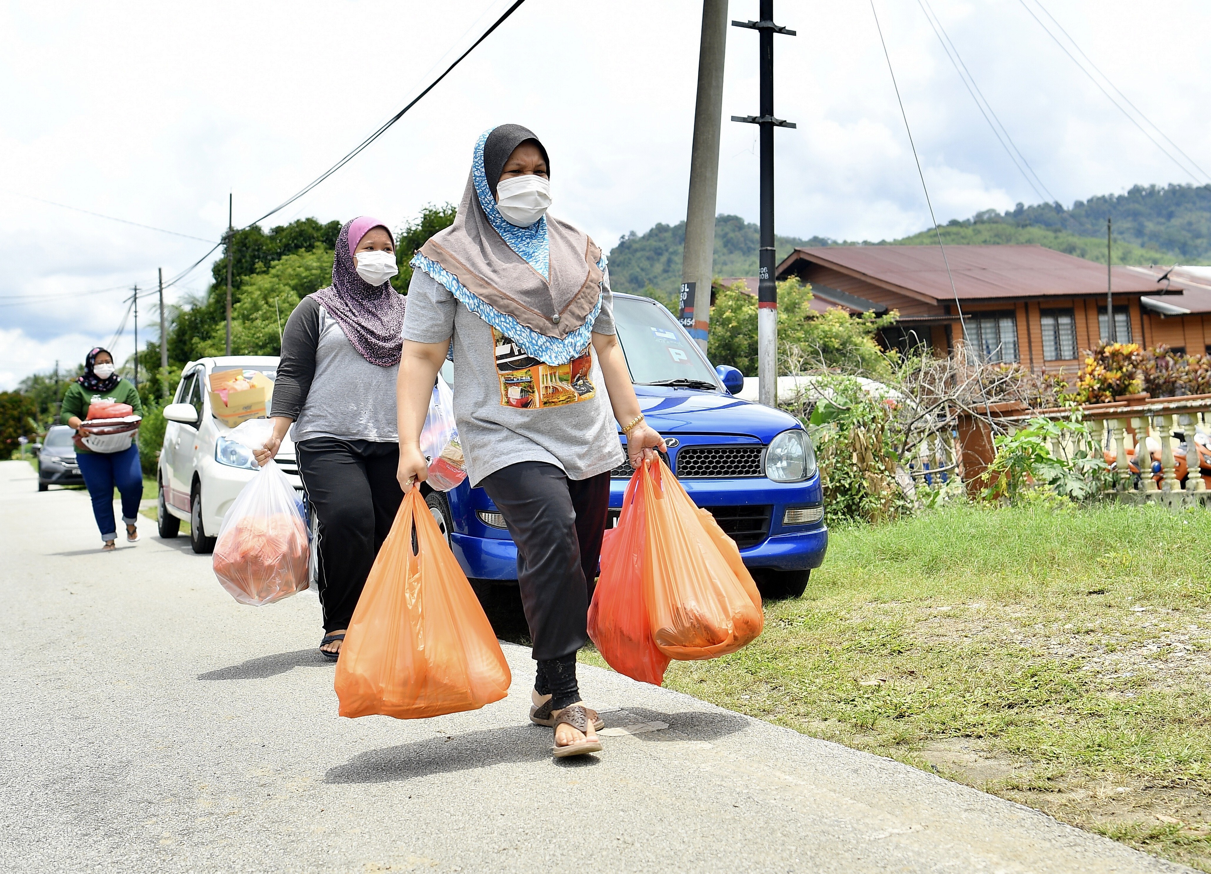 Malaysians carry shopping bags full of supplies as they walk down a deserted road amid the country’s lockdown. Photo: DPA