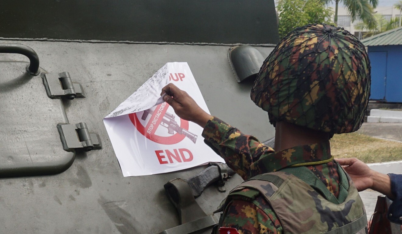 A soldier removes a protest sign denouncing the military coup from an armoured vehicle outside the Central Bank of Myanmar in Yangon. Photo: AFP