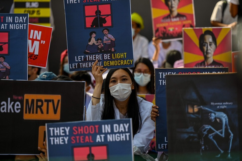 Protesters holds signs as they demonstrate against the military coup in front of the US embassy in Yangon on Monday. Photo: AFP