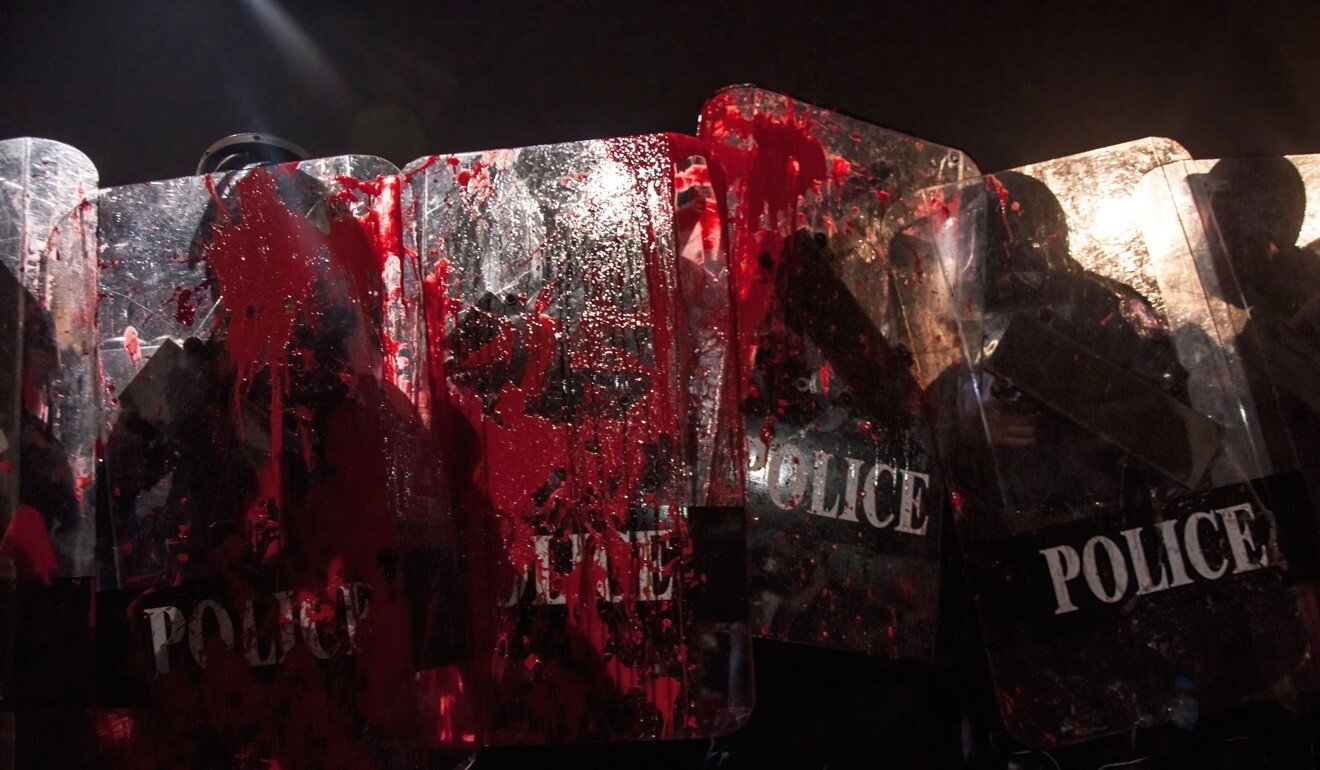Pro-democracy protesters throw paint at riot police during clashes following a demonstration at the Democracy Monument. Photo: DPA