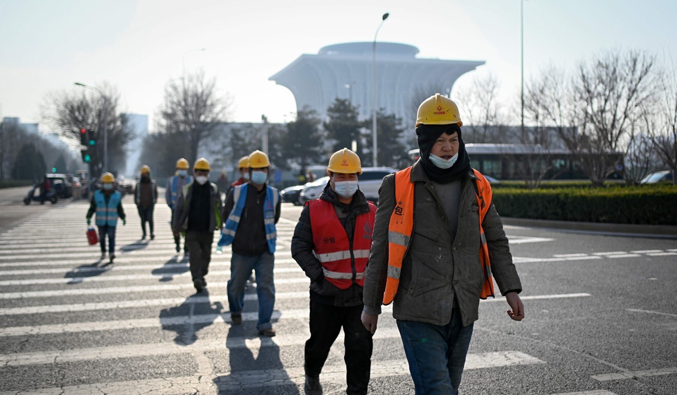 Workers cross a street in Beijing. Photo: AFP