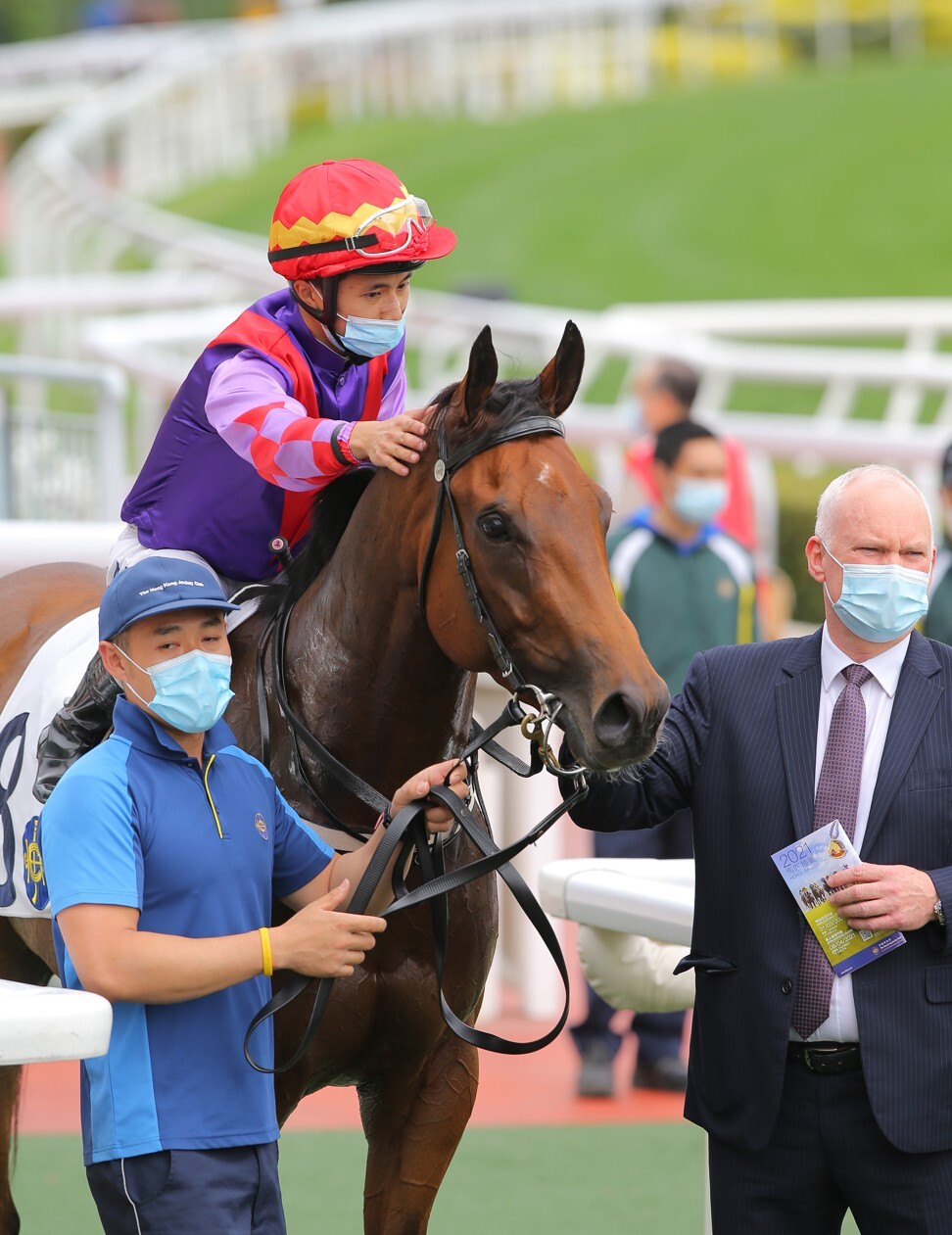 Jockey Matthew Poon gives Summit Cheers a pat as trainer David Hall looks on.