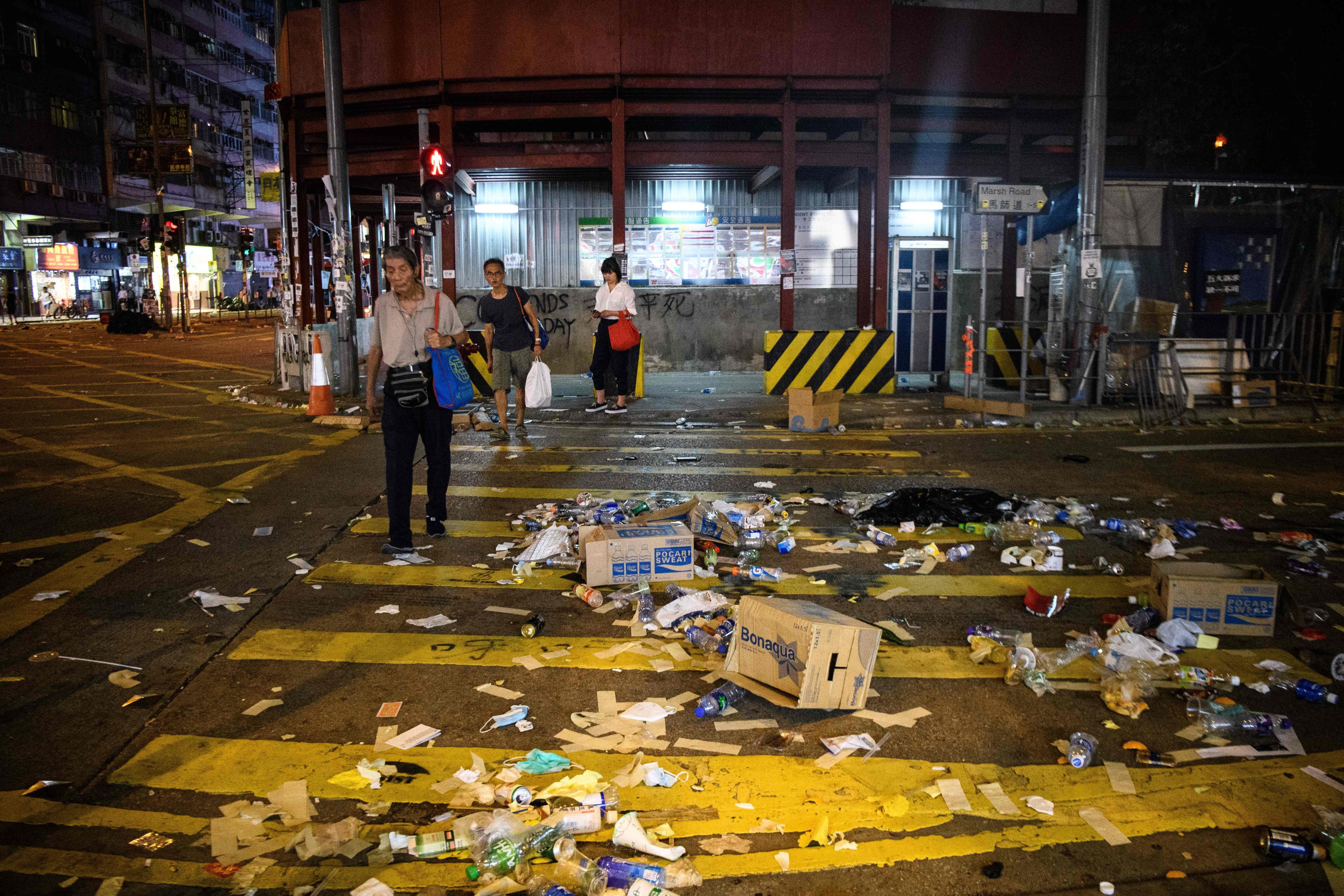 People cross a road covered in debris after violent demonstrations in Hong Kong in October 2019, as the city observed the National Day holiday to mark the 70th anniversary of communist China's founding. Photo: AFP