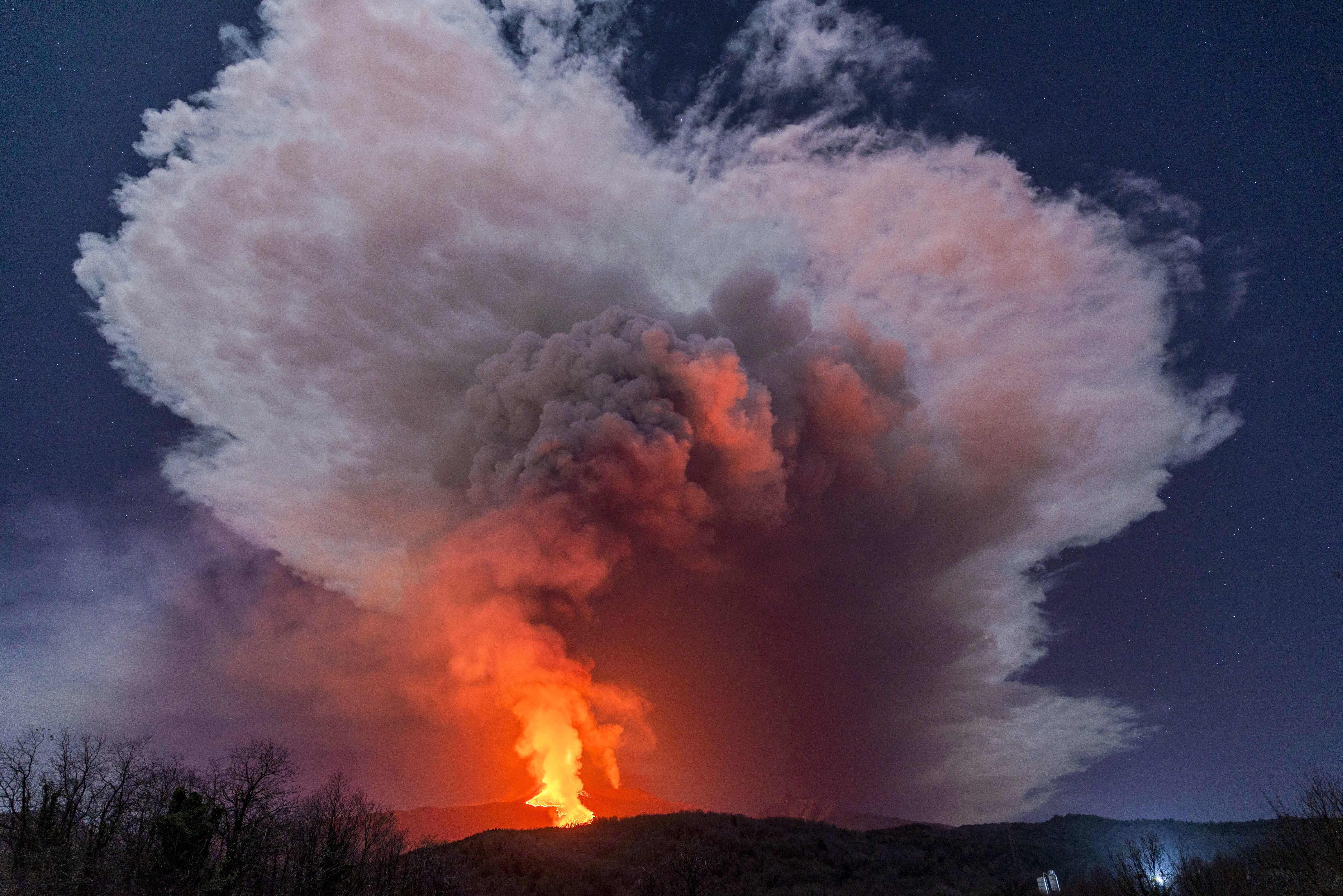 A fiery river of glowing lava flows on the north-east side of the Mount Etna volcano engulfed with ashes and smoke near Milo, Sicily. Photo: AP
