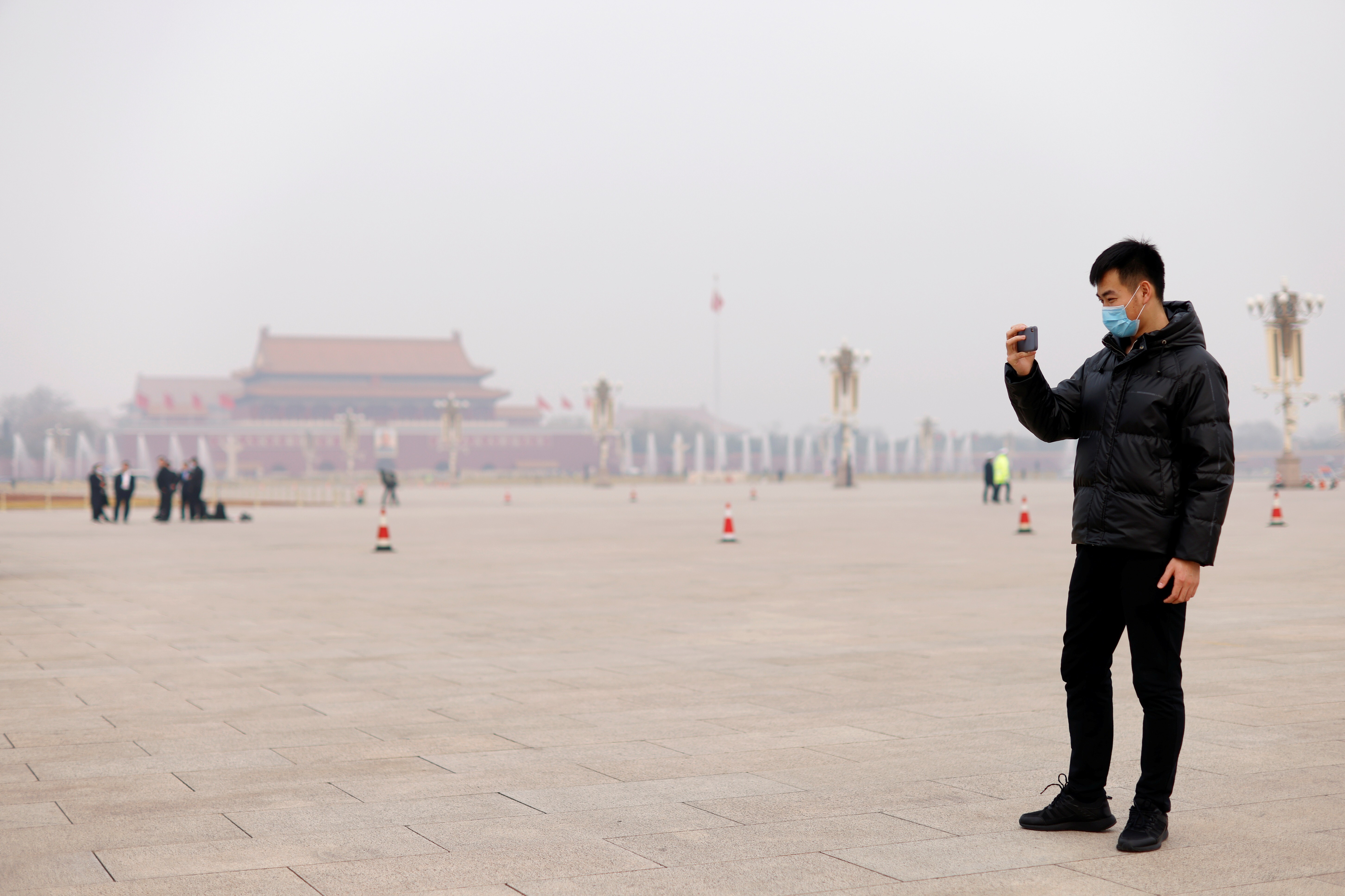 A man in Tiananmen Square holds his mobile phone while shrouded in smog, before the closing session of the Chinese People's Political Consultative Conference (CPPCC) at the Great Hall of the People on a polluted day in Beijing, China on March 10, 2021. Photo: Reuters