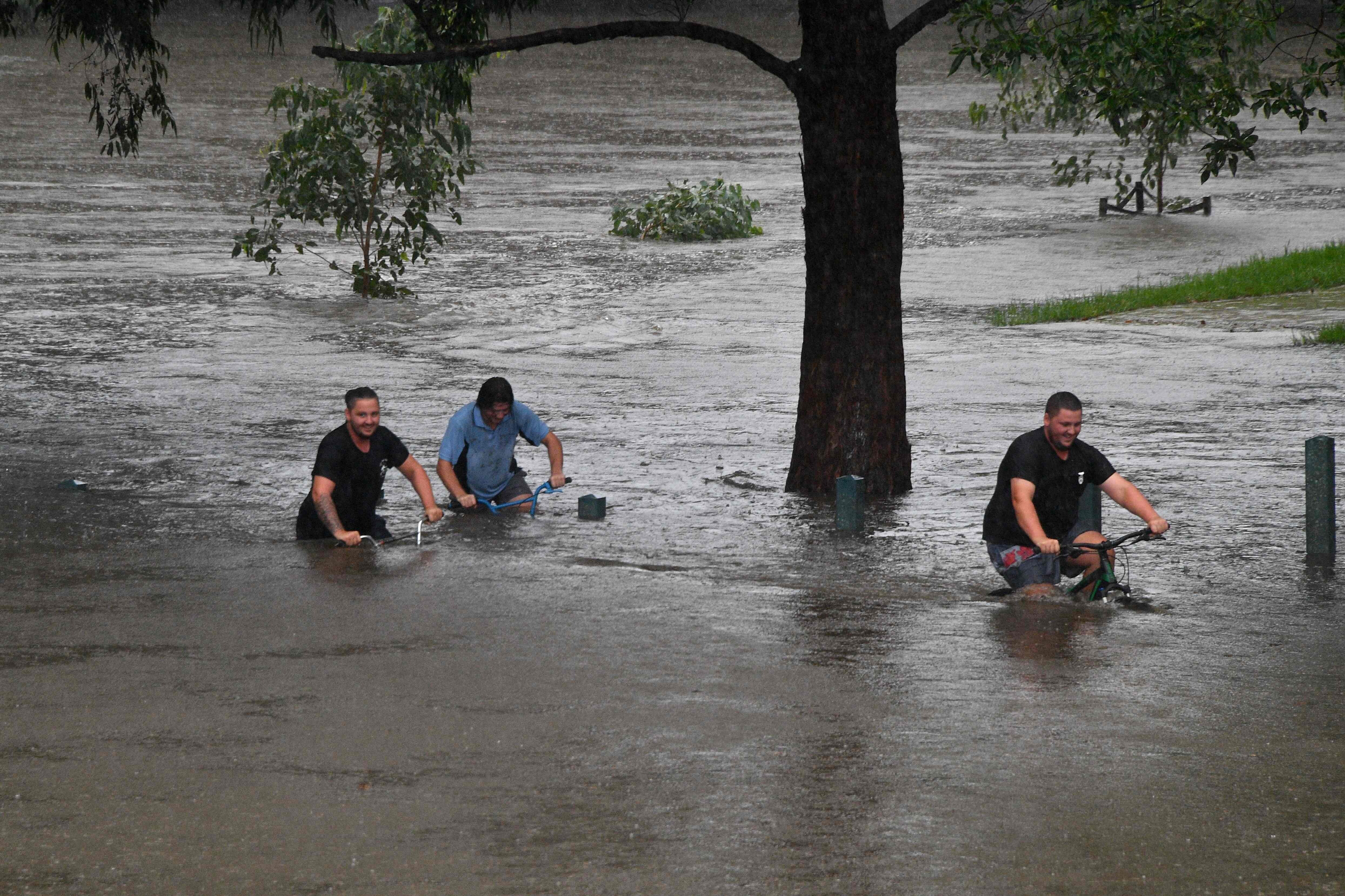 People ride bicycles through a flooded park in Penrith, Sydney. Photo: AFP