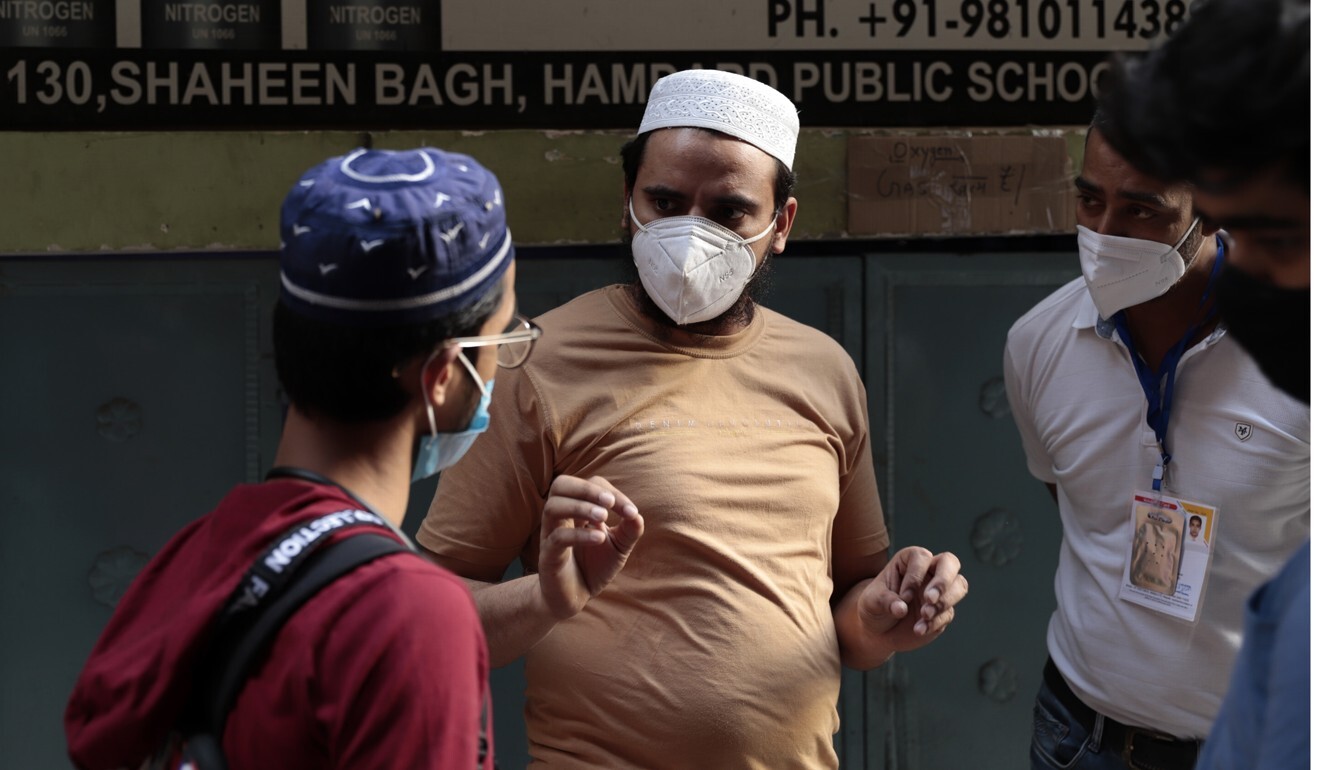Mohammad Waseem speaks to people outside his shop about oxygen supplies. Photo: Shahid Tantray