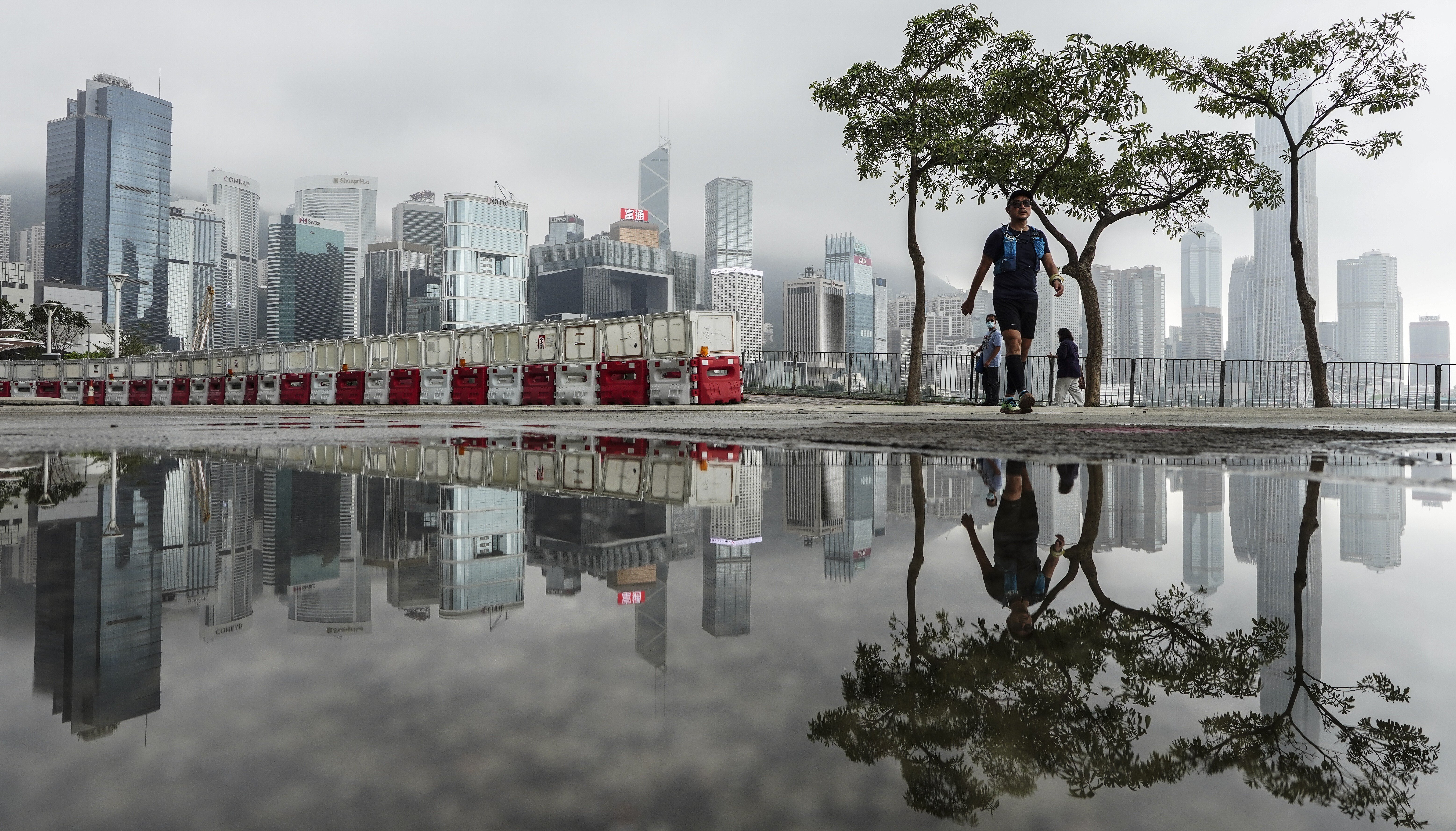 People walking cross the Wan Chai waterfront with the Central District area as background. Photo: SCMP / Robert Ng