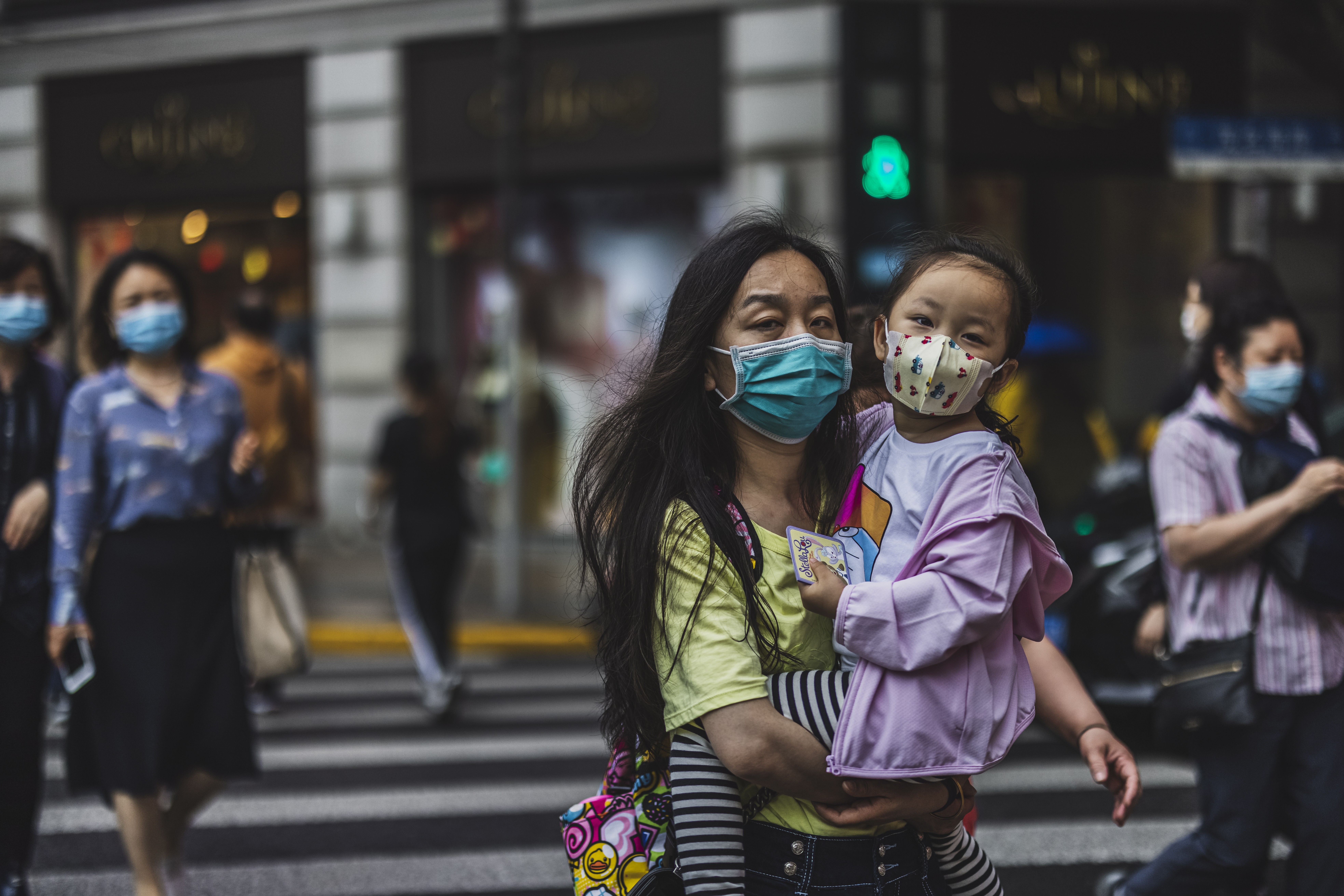 People cross the street in Shanghai on May 11. China must make a whole-of-society push to raise the birth rate, and this must include making childcare more accessible to working families. Photo: EPA-EFE