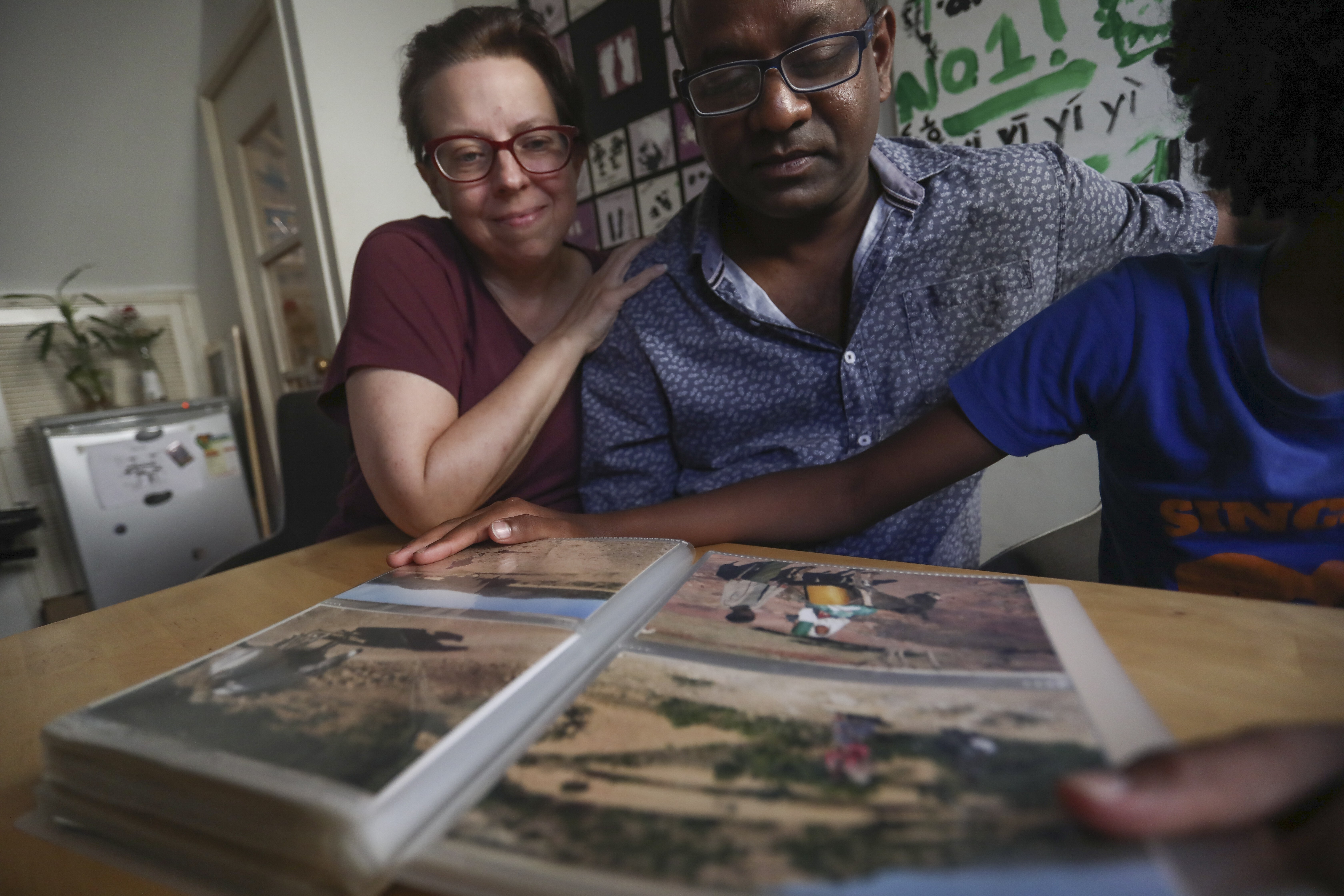 Karen Arndt (left) and Chris Prosper, with their 10-year-old son, who was adopted from Ethiopia’s Tigray region, look through their photo album, in their home in Shek O. Photo: Jonathan Wong