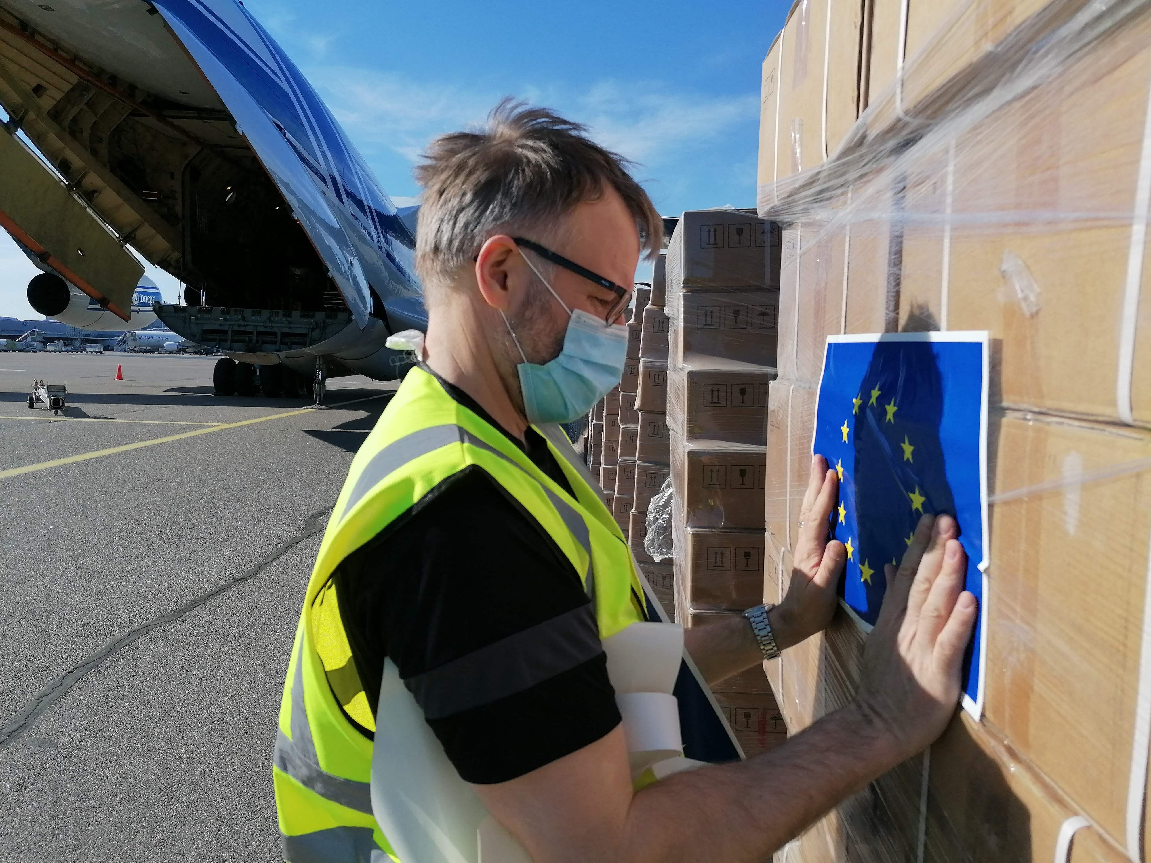 A Red Cross worker sticks an EU flag sticker on a shipment of ventilators from Germany before it is loaded onto a cargo plane bound for New Delhi, India, at Helsinki airport in Finland on May 11. A total of 18 EU member states have pledged medical aid to India. Photo: AFP