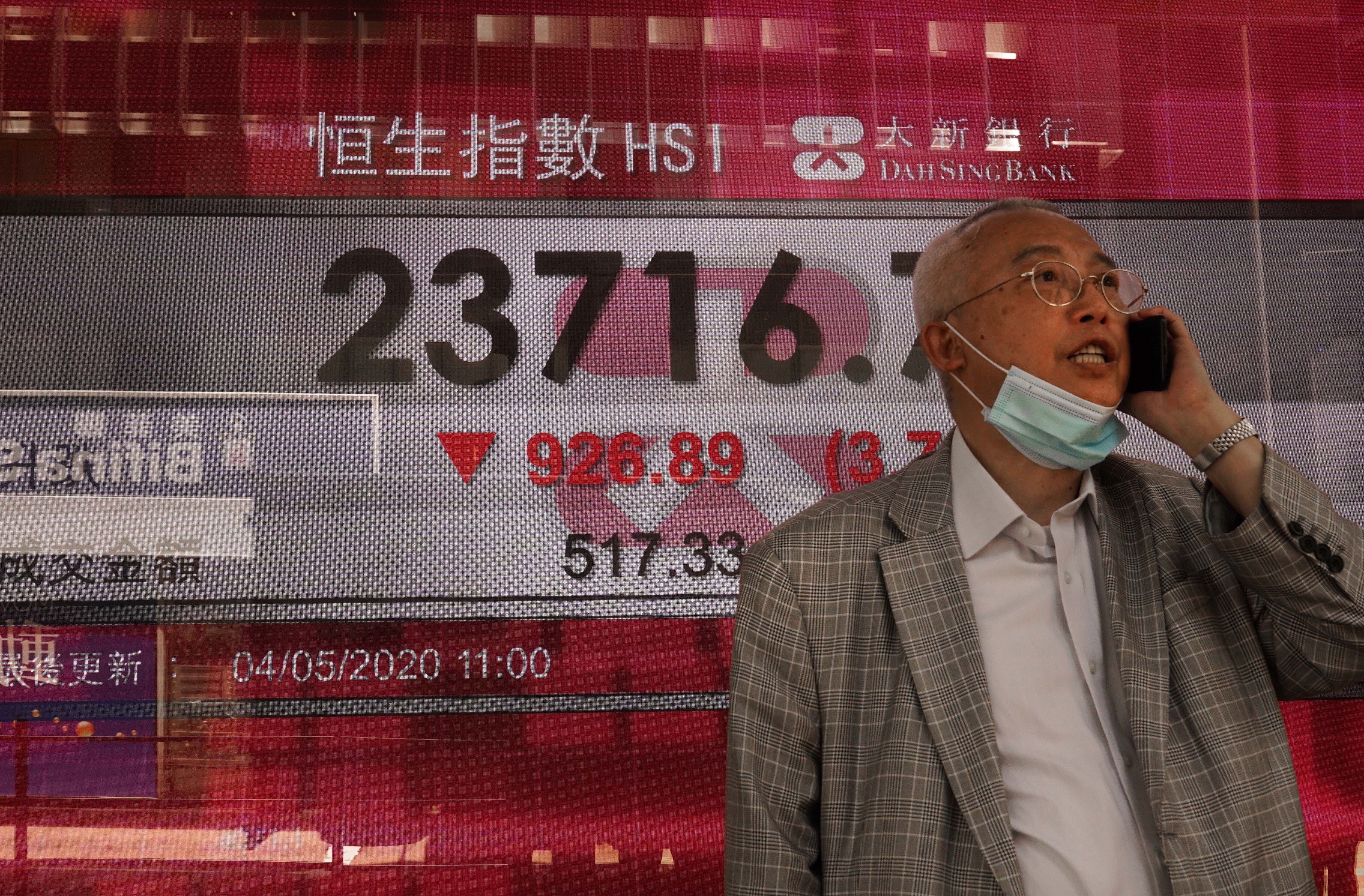 A man stops next to an electronic board showing the Hong Kong share index on May 4, 2020. Photo: AP