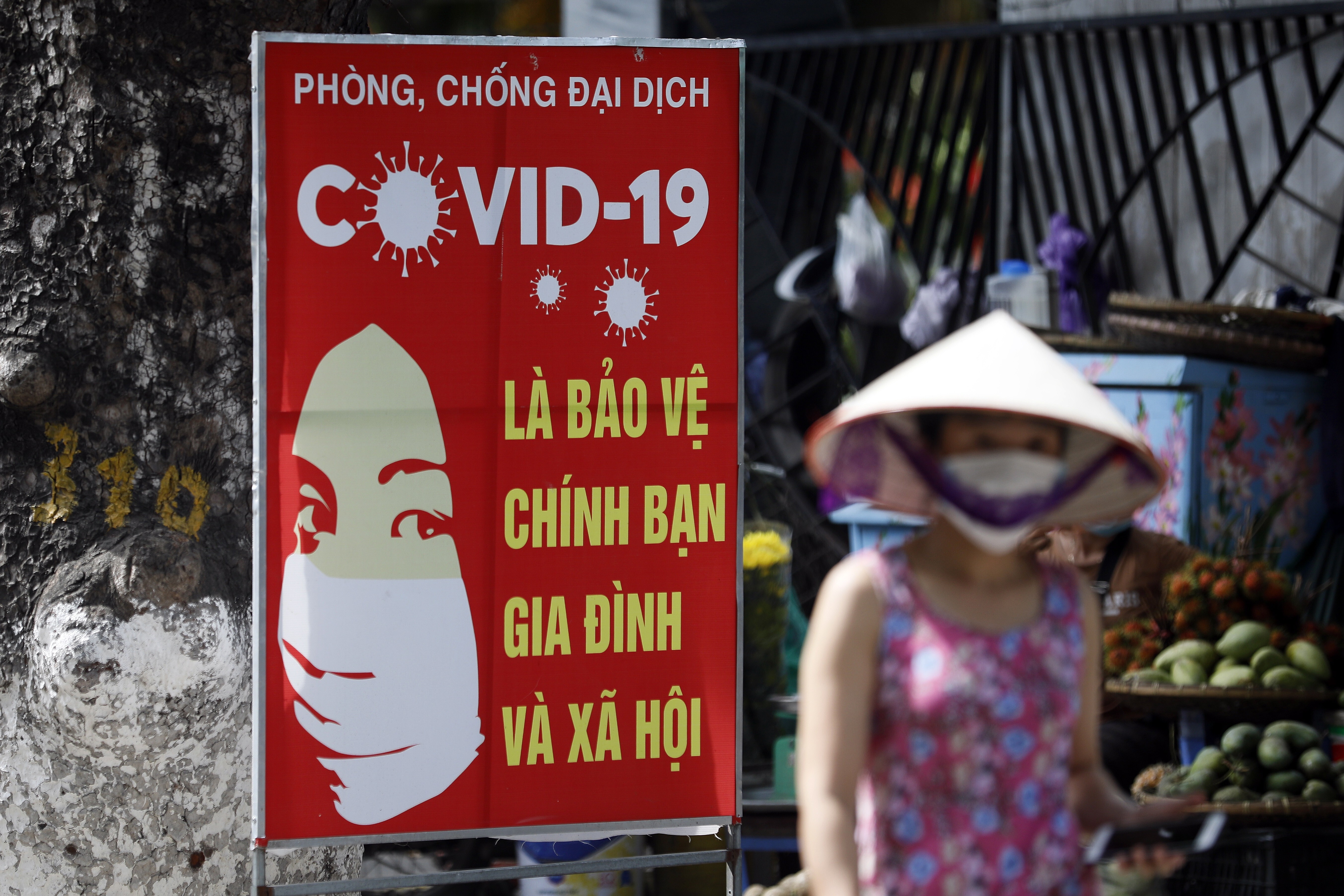 A woman walks past a sign bearing Covid-19 prevention advice in Hanoi. Photo: EPA-EFE