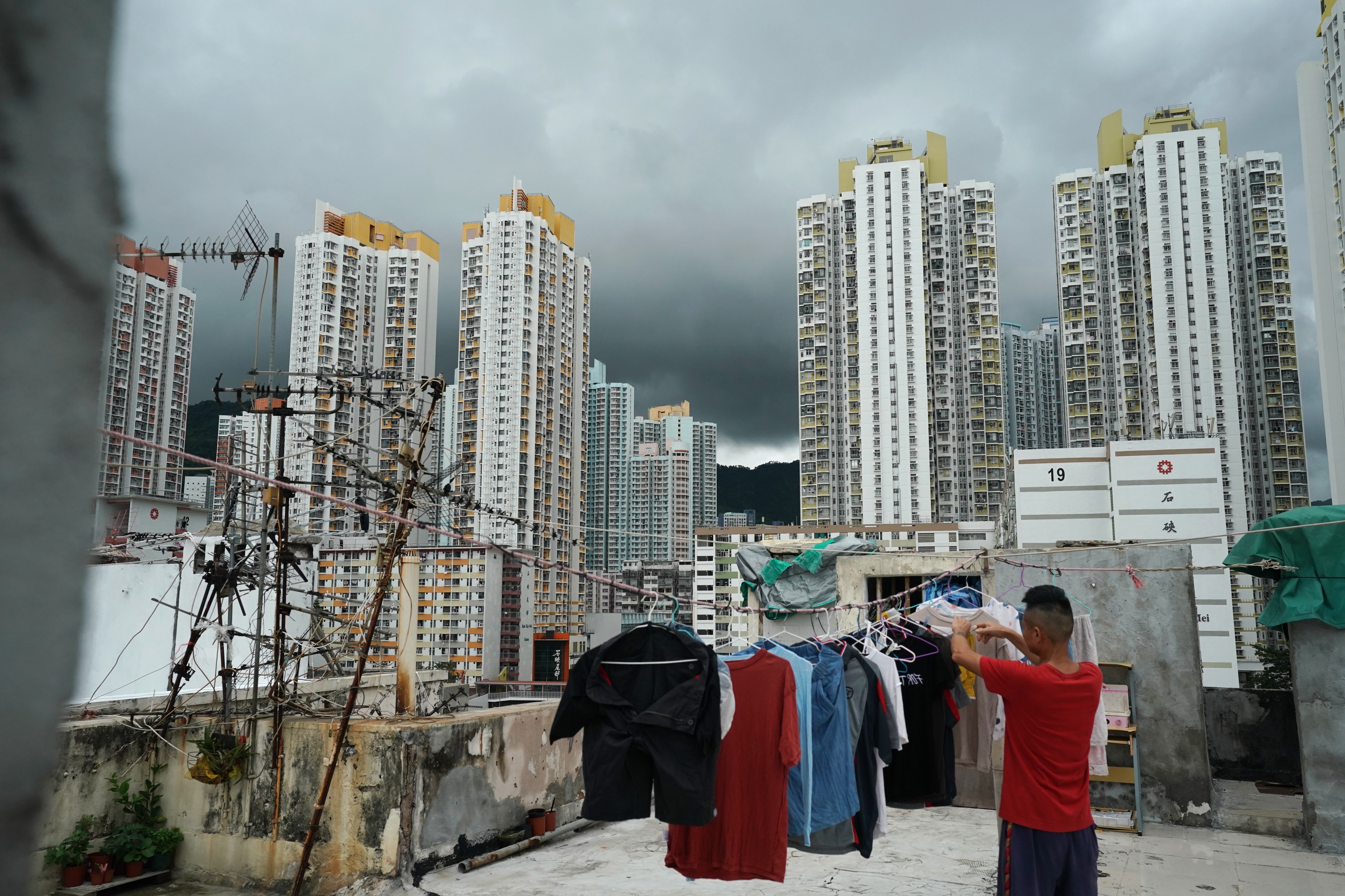 A man hangs his clothes to dry on the rooftop of a building in Sham Shui Po against the backdrop of public housing flats. Photo: Felix Wong
