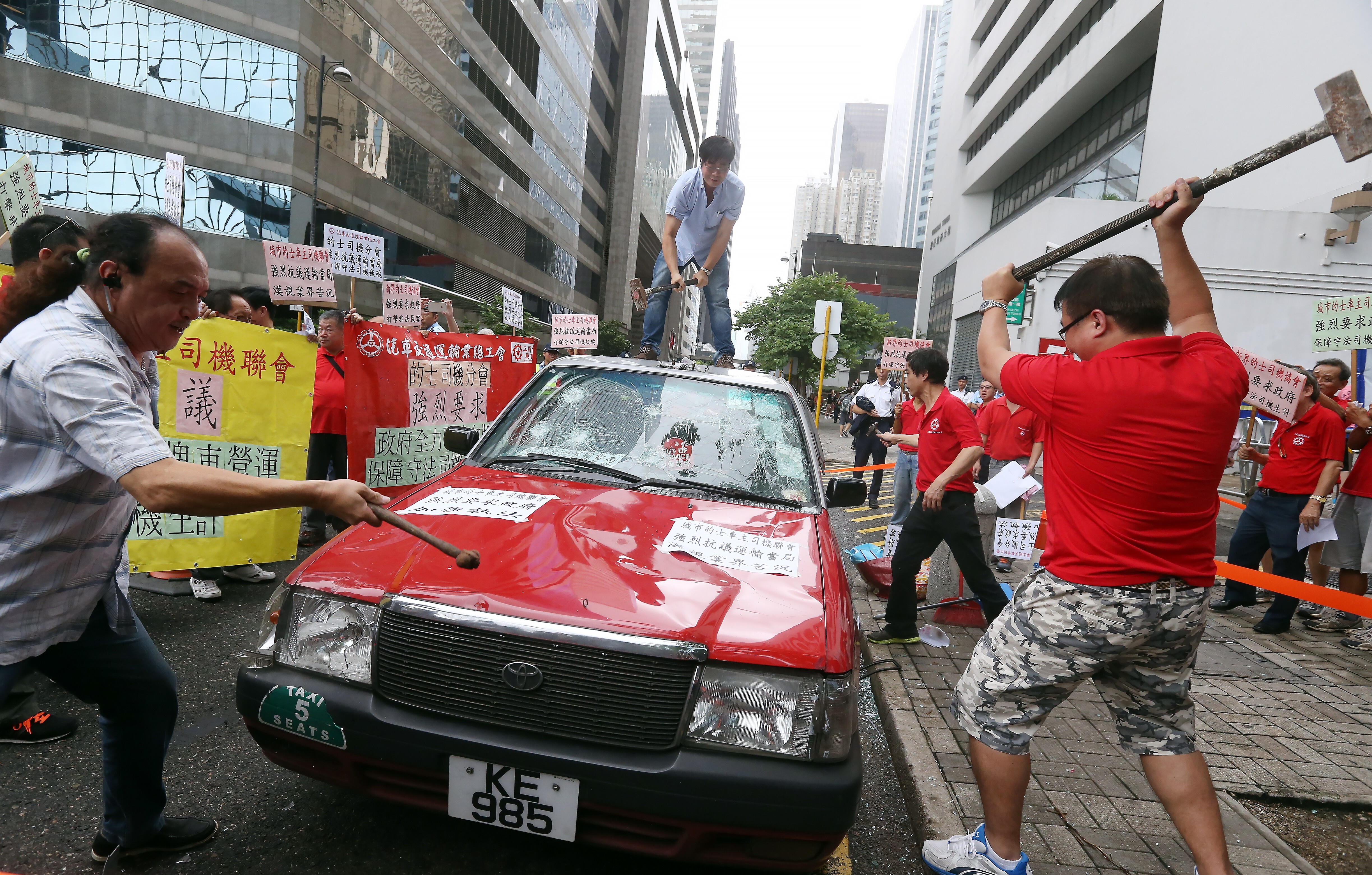 Taxi drivers smash one of their own vehicles as they call on the Hong Kong government to ban ride-hailing services like Uber, in Wan Chai in July 2015. The tussle continues in 2021. Photo: Dickson Lee