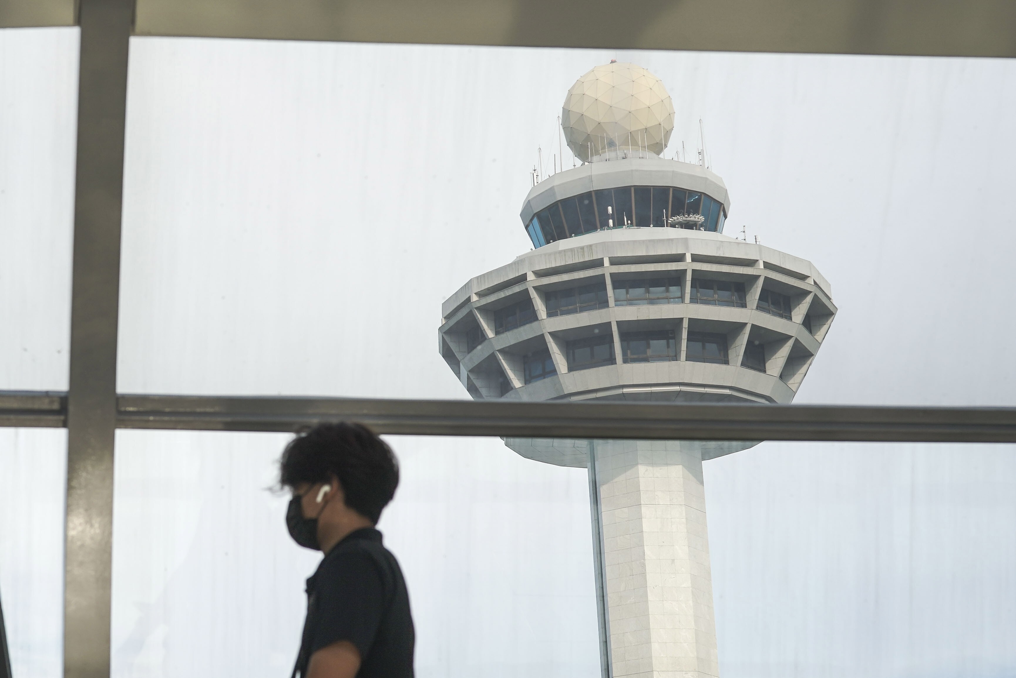 A man passes the control tower of Singapore’s Changi Airport. Photo: EPA