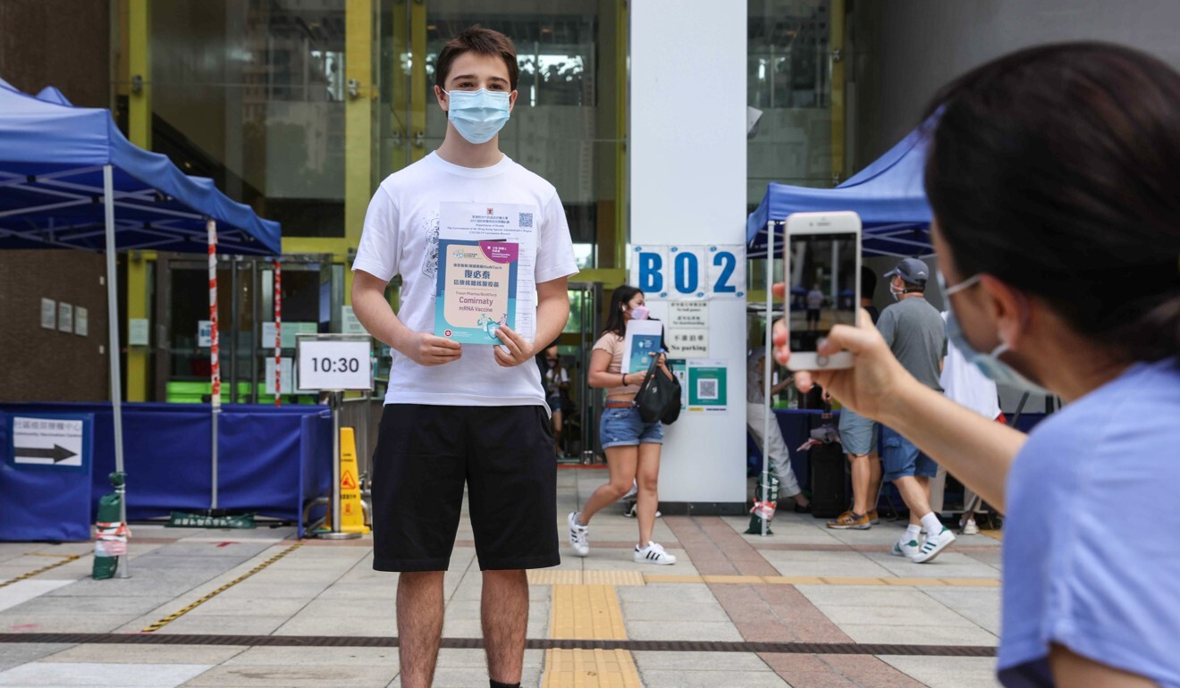 Javier Adrada Rodriguez, has his photo taken by his mother after getting his first jab at Sun Yat Sen Memorial Park Sports Centre. Photo: Nora Tam