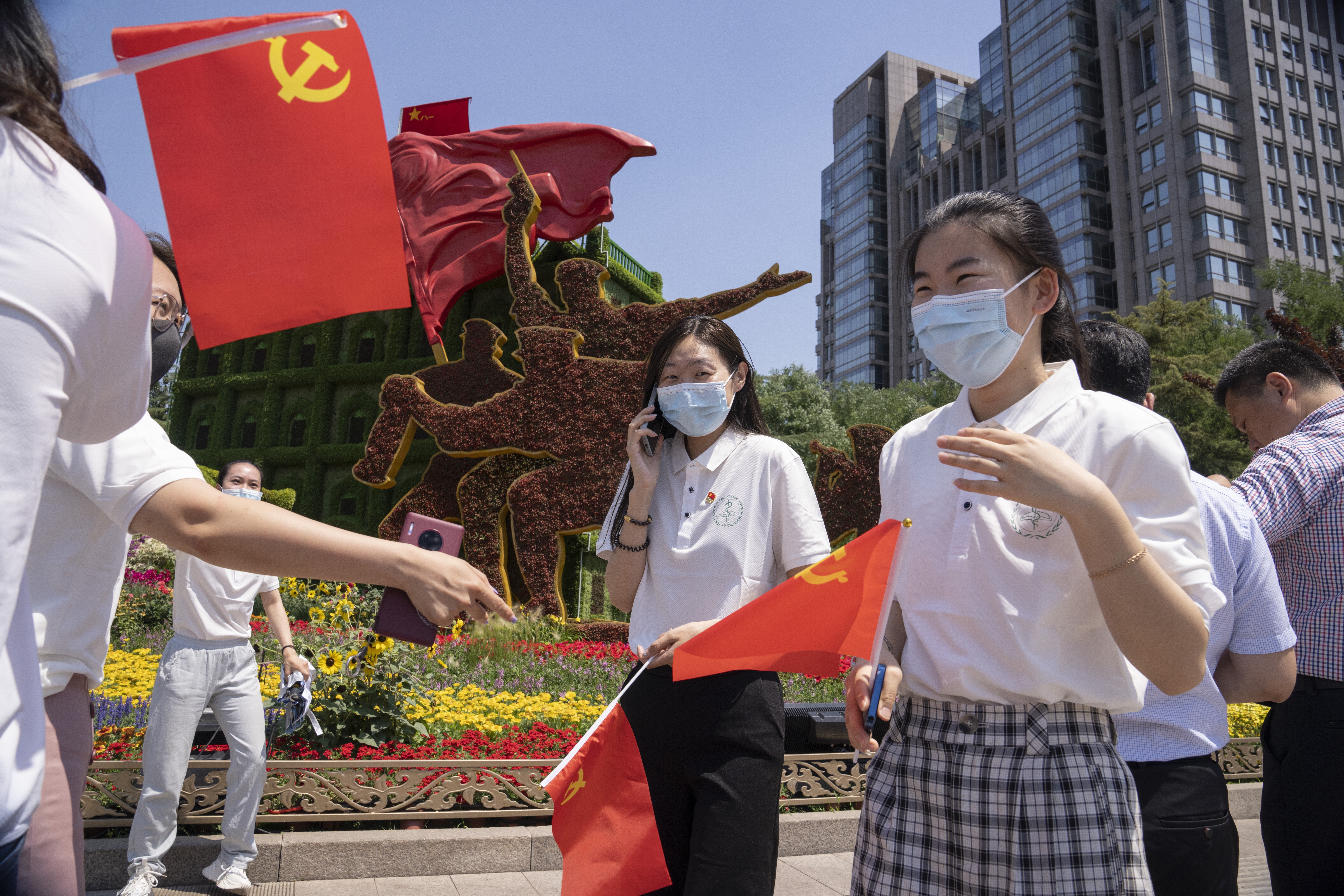 Communist Party members hold party flags in front of a floral decoration for the upcoming 100th anniversary of the founding of China's ruling Communist Party in Beijing. Photo: AP Photo