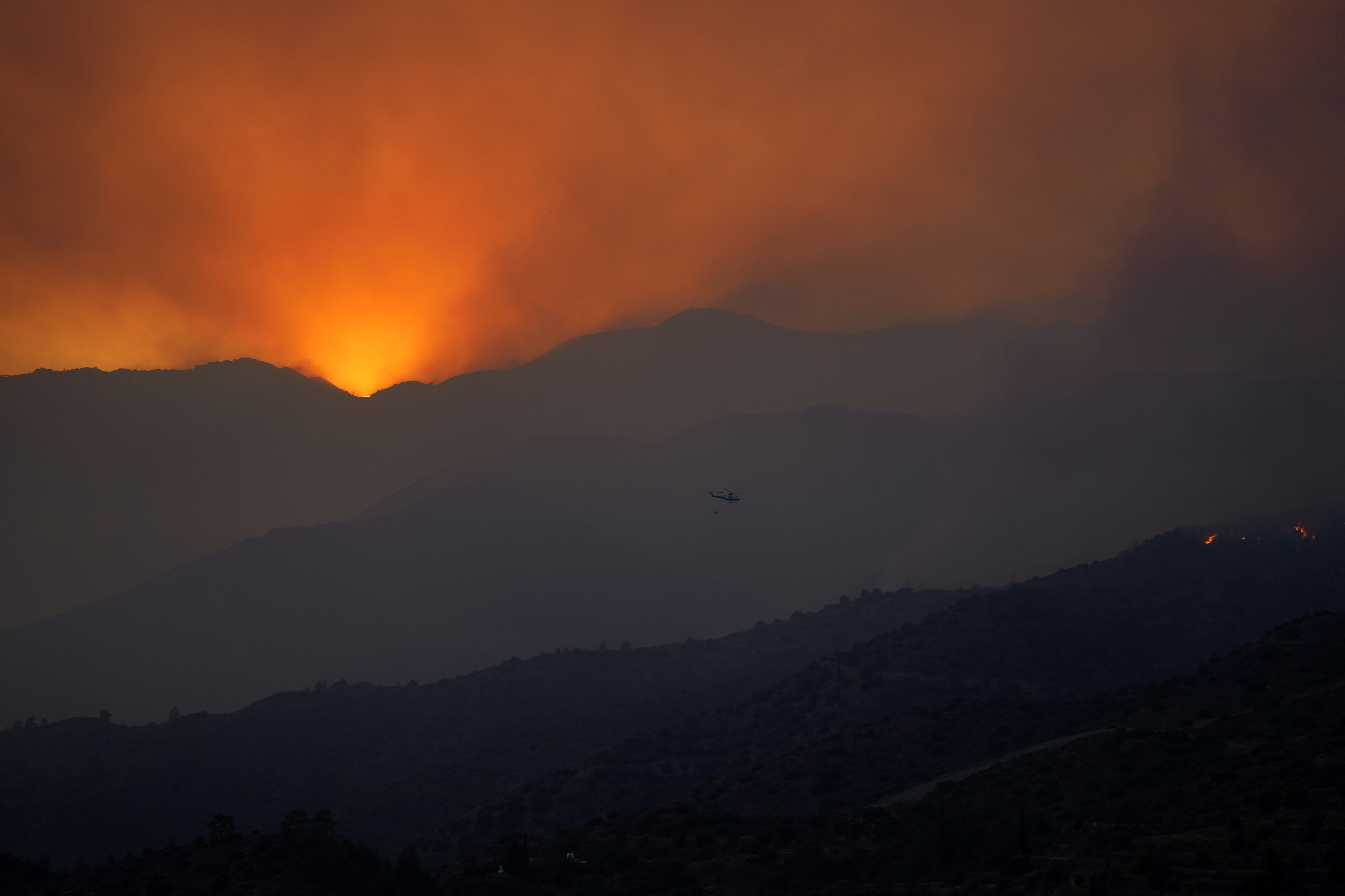 A helicopter flies towards the smoke over fire in the Larnaca mountain region in Cyprus on Saturday. Photo: AP