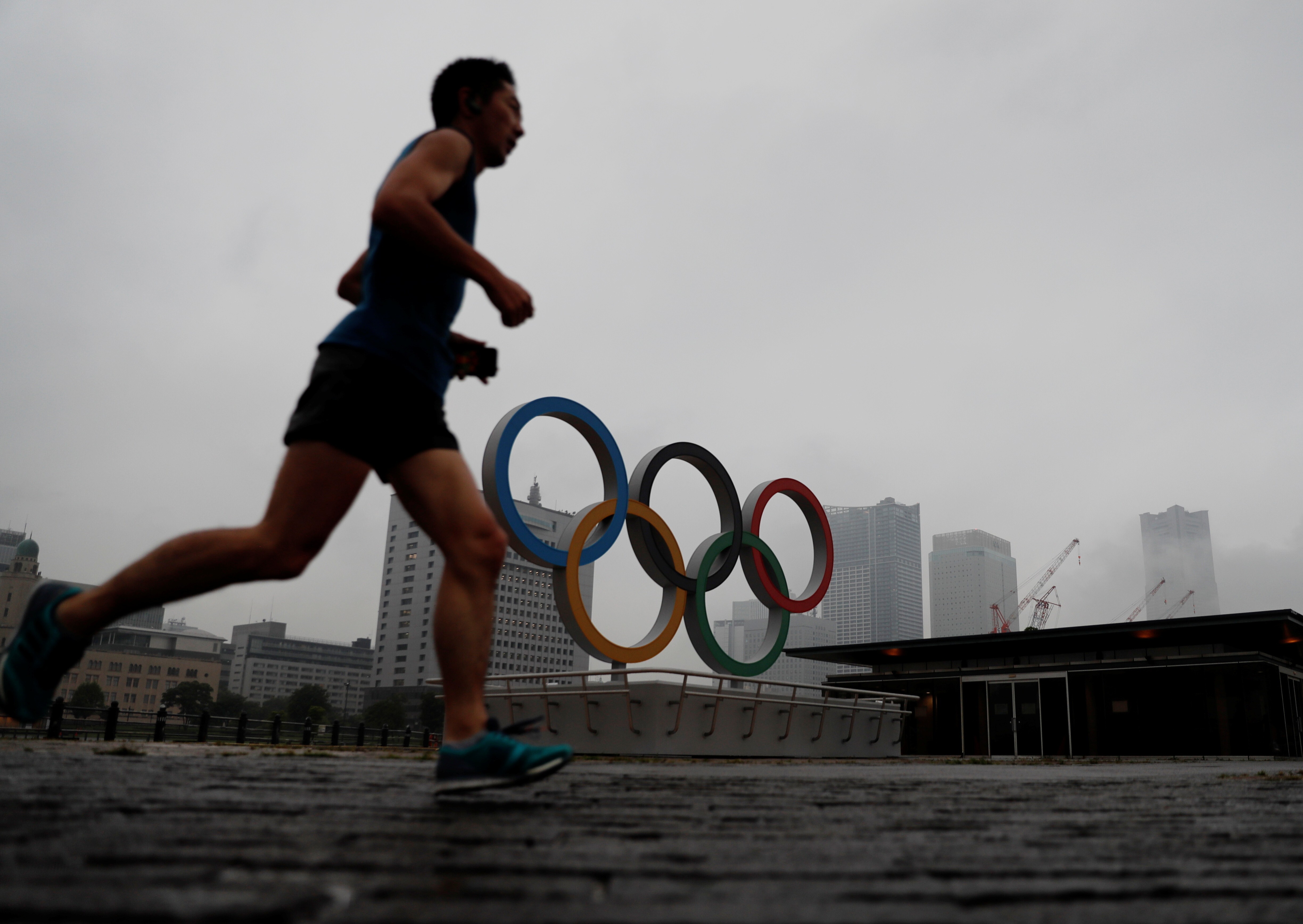 A jogger runs past a newly installed Olympic rings in Yokohama, Japan. Photo: Reuters