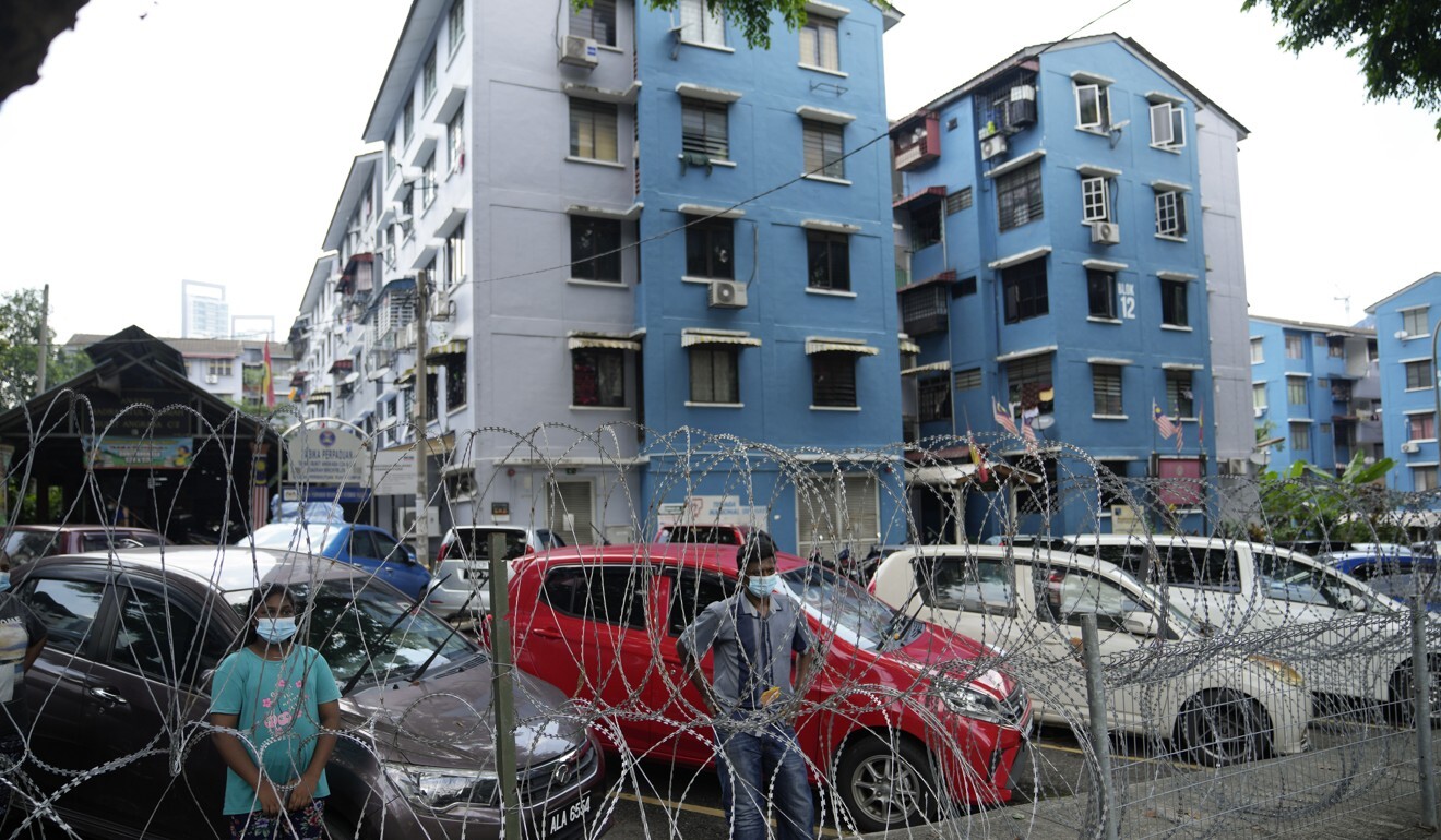 Kuala Lumpur residents under movement restrictions wait behind barbed wire for food to be delivered. Photo: AP