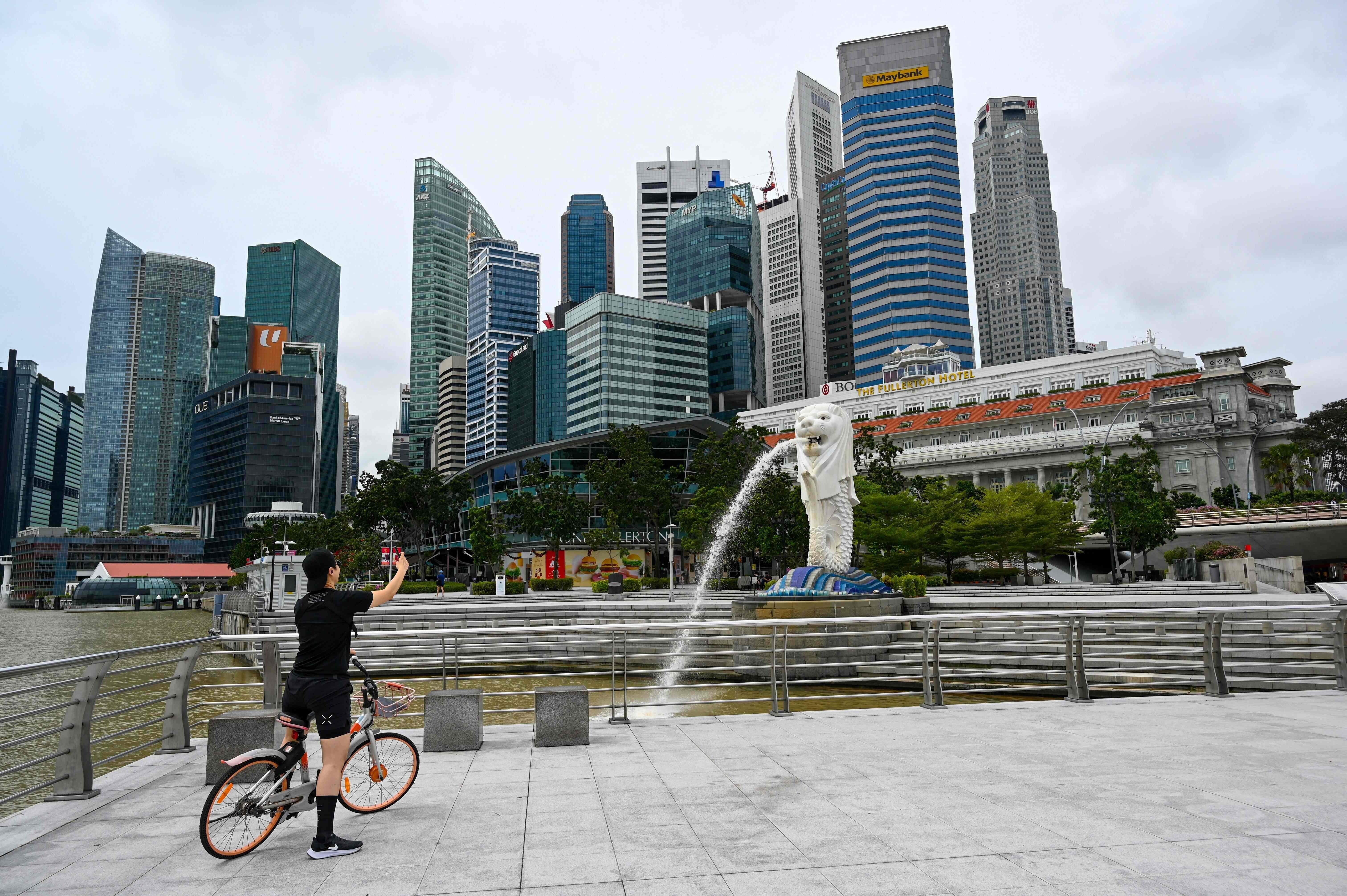 A cyclist takes a photo in front of the Merlion statue in Singapore. Photo: AFP