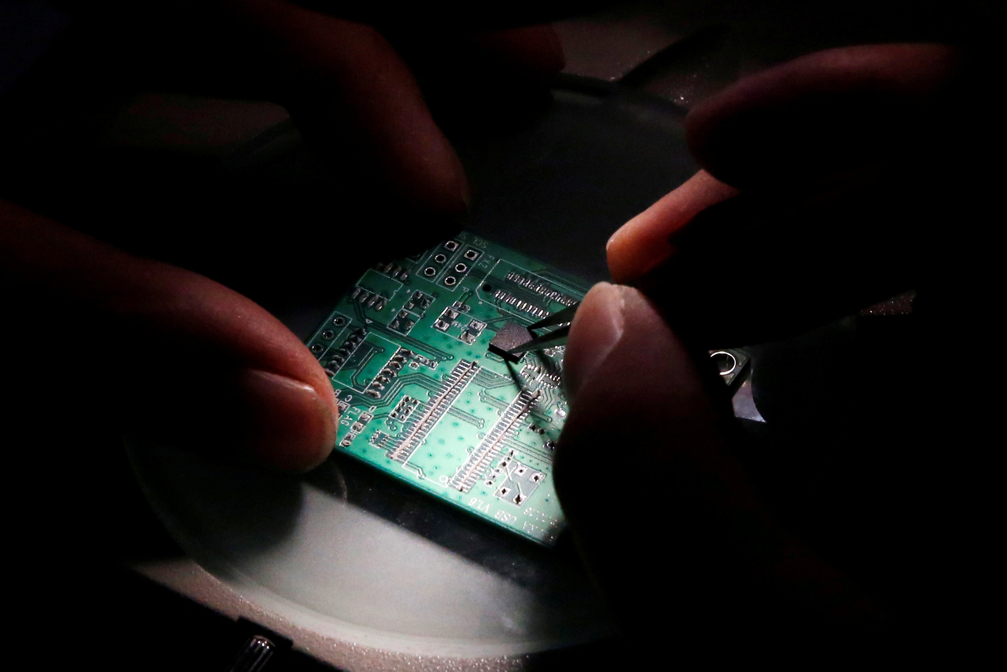 A researcher places a semiconductor on a printed circuit board during research work at Tsinghua Unigroup in Beijing. Photo: Reuters