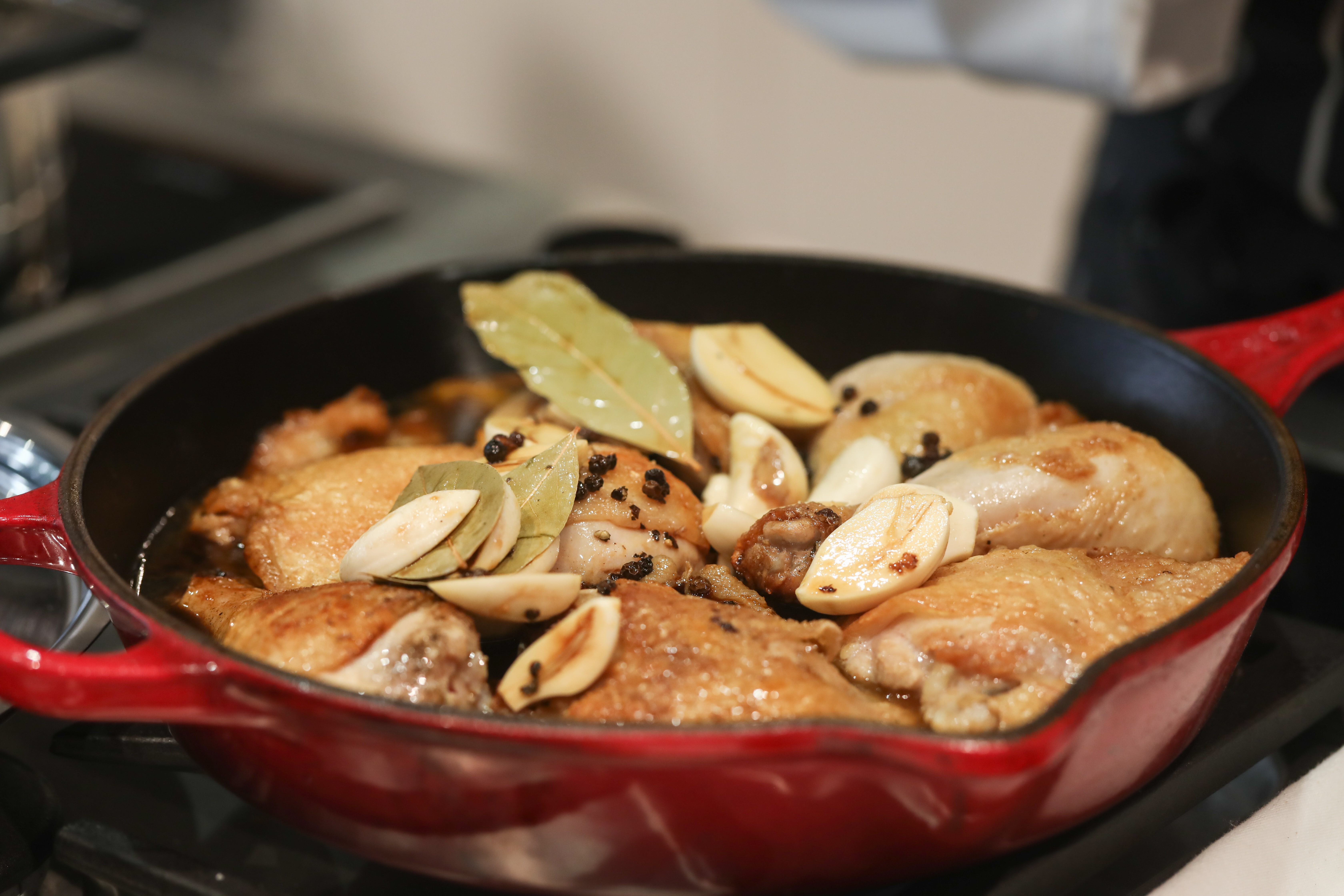 Chicken adobo simmers in a pan. Photo: Jonathan Wong
