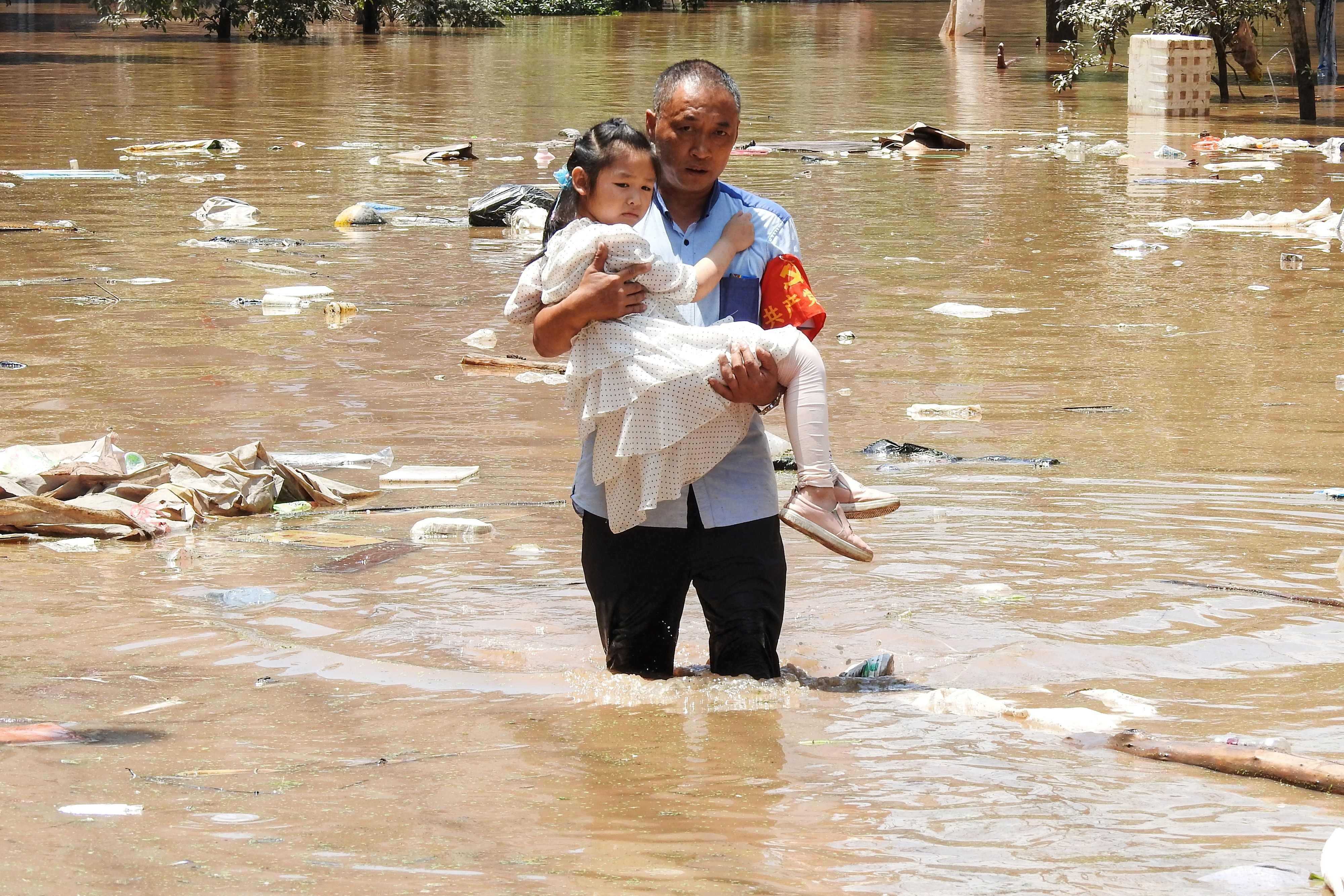 A village official evacuates a child from a flooded area on Monday following heavy rains in Dazhou, Sichuan province. Photo: AFP