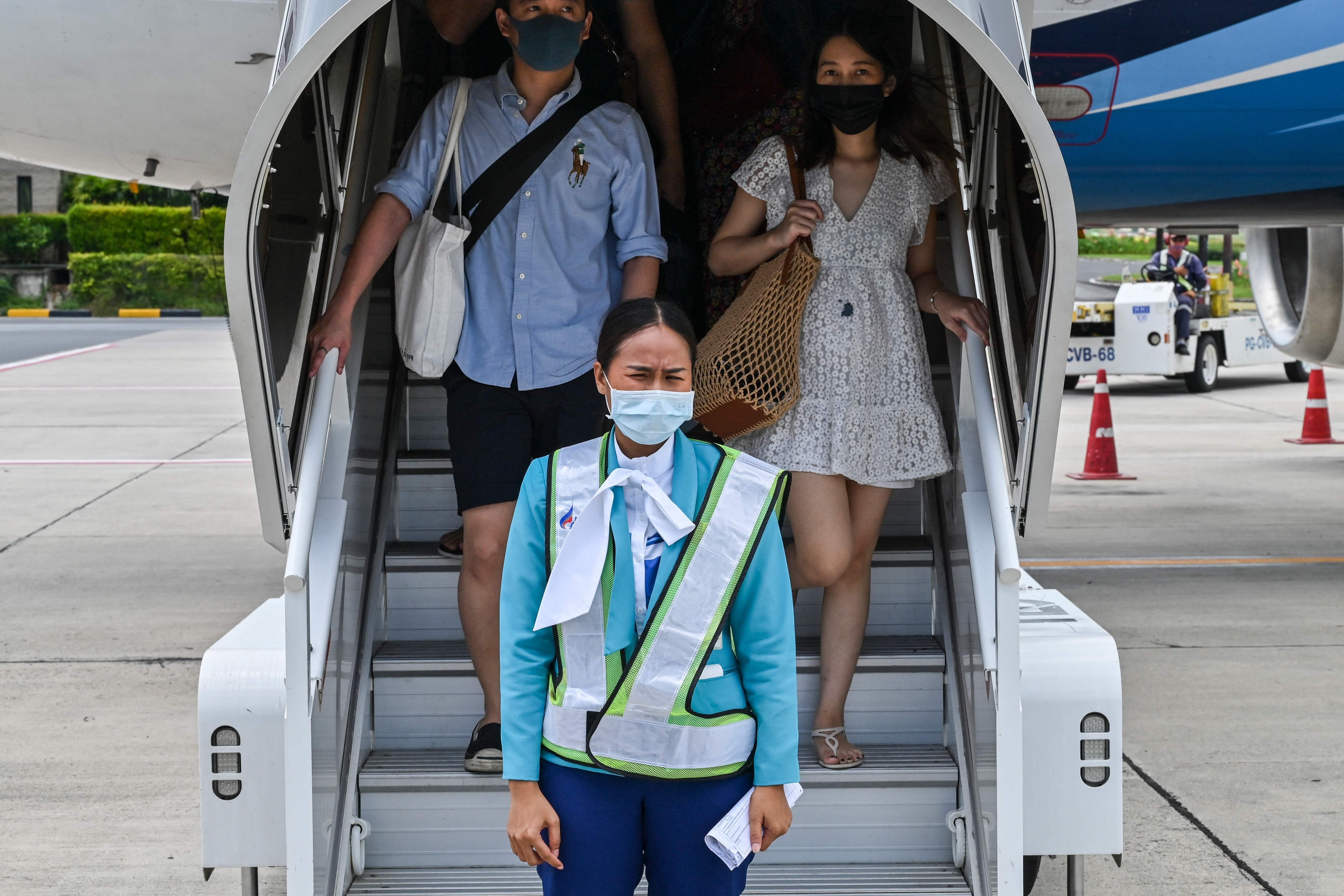 Tourists wearing face masks disembark after arriving at Koh Samui in Thailand. Photo: AFP