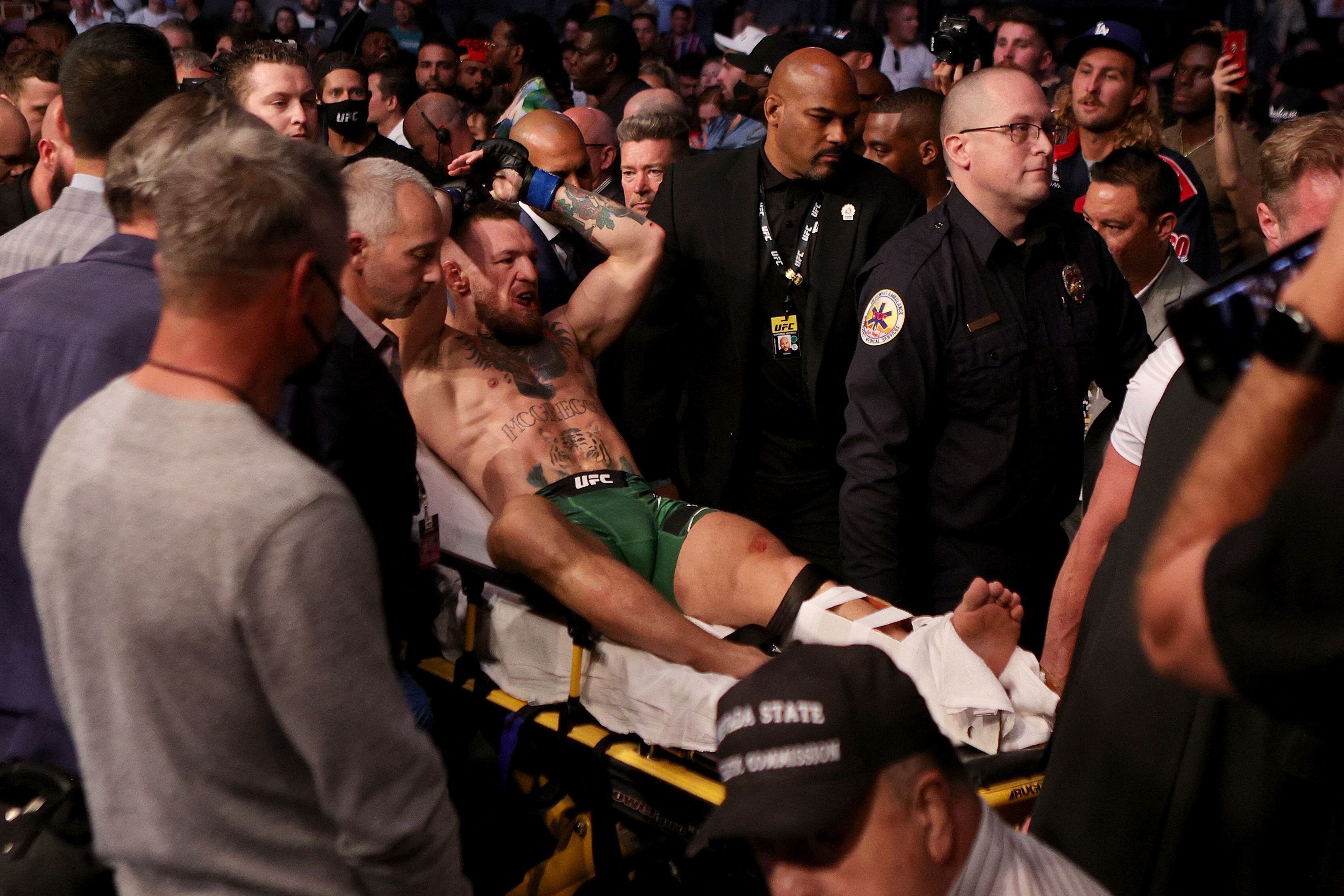 Conor McGregor is carried out of the arena on a stretcher after breaking his leg against Dustin Poirier at UFC 264. Photo: AFP