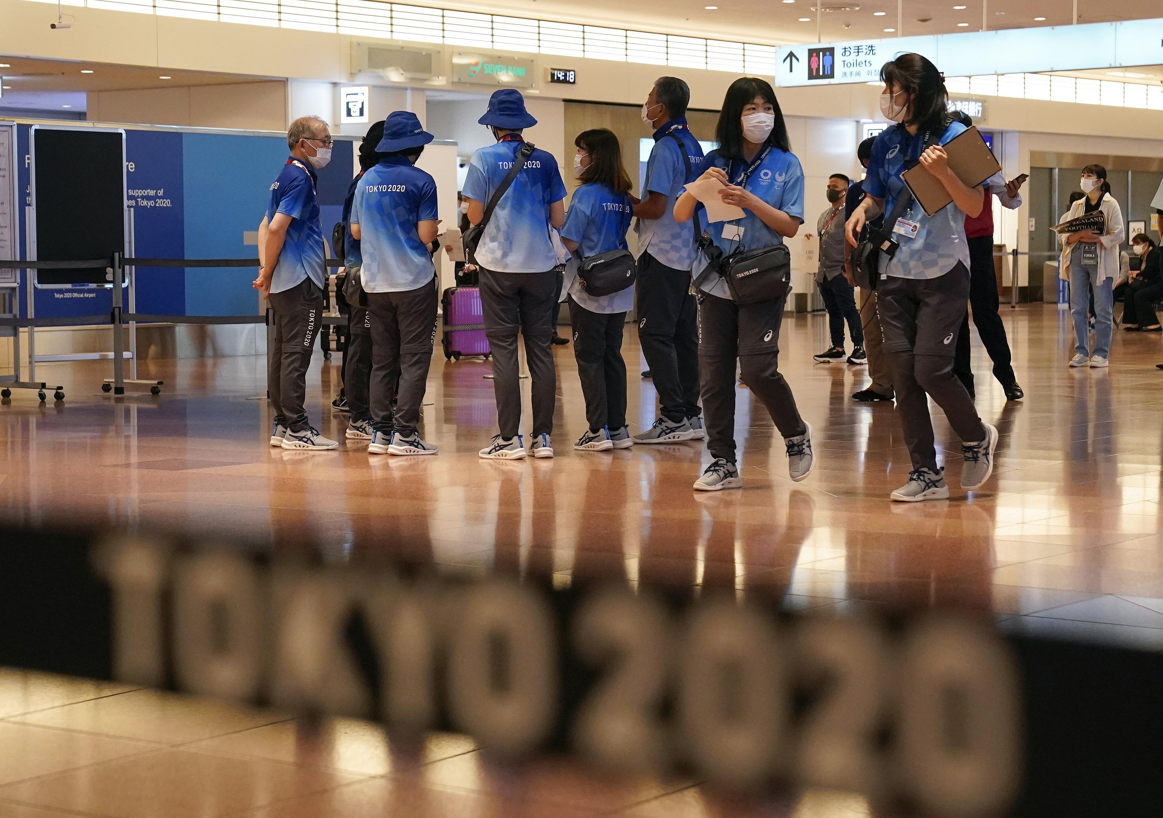 Tokyo 2020 volunteer staff wait for overseas athletes and coaches at Tokyo International Airport on July 8. Photo: EPA