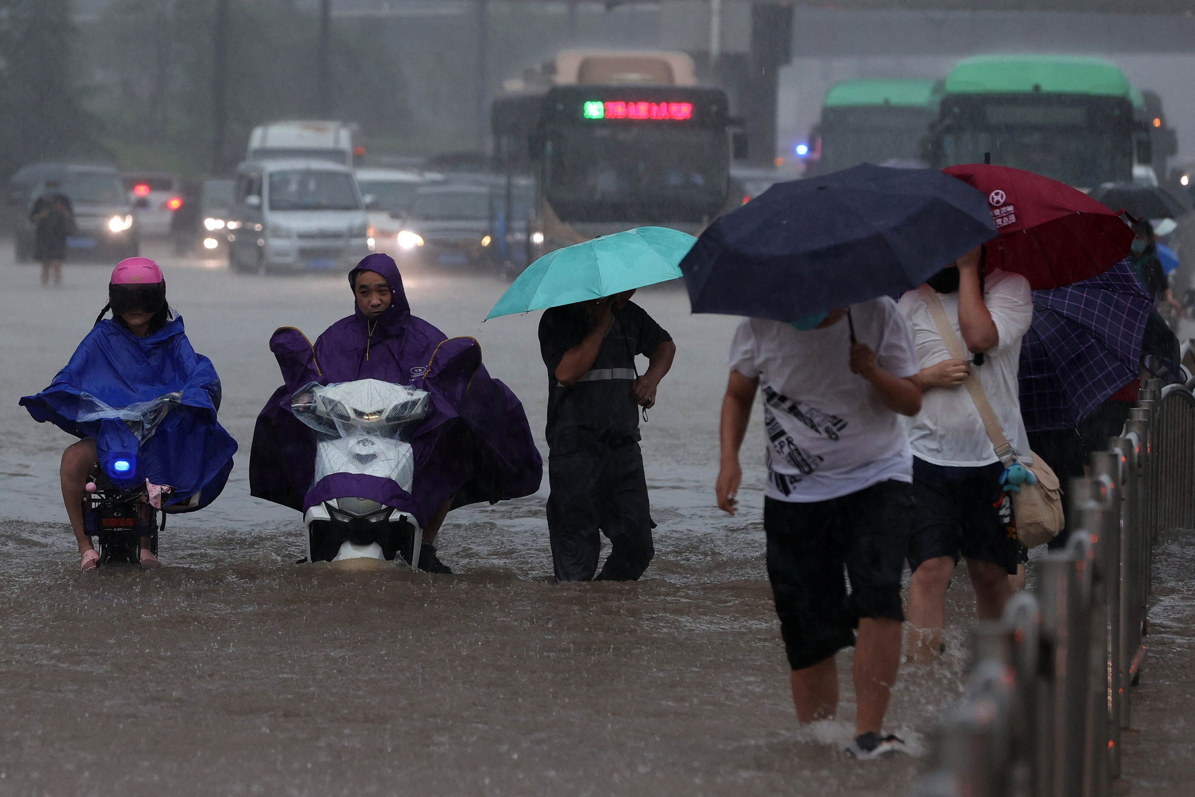 People wade through floodwater in Zhengzhou, Henan on Tuesday after heavy rains. Photo: AFP