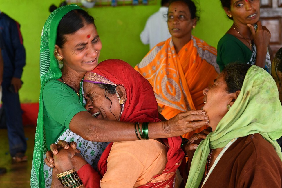 Villagers console a woman who lost a relative following a landslide in Taliye, India. Photo: AFP