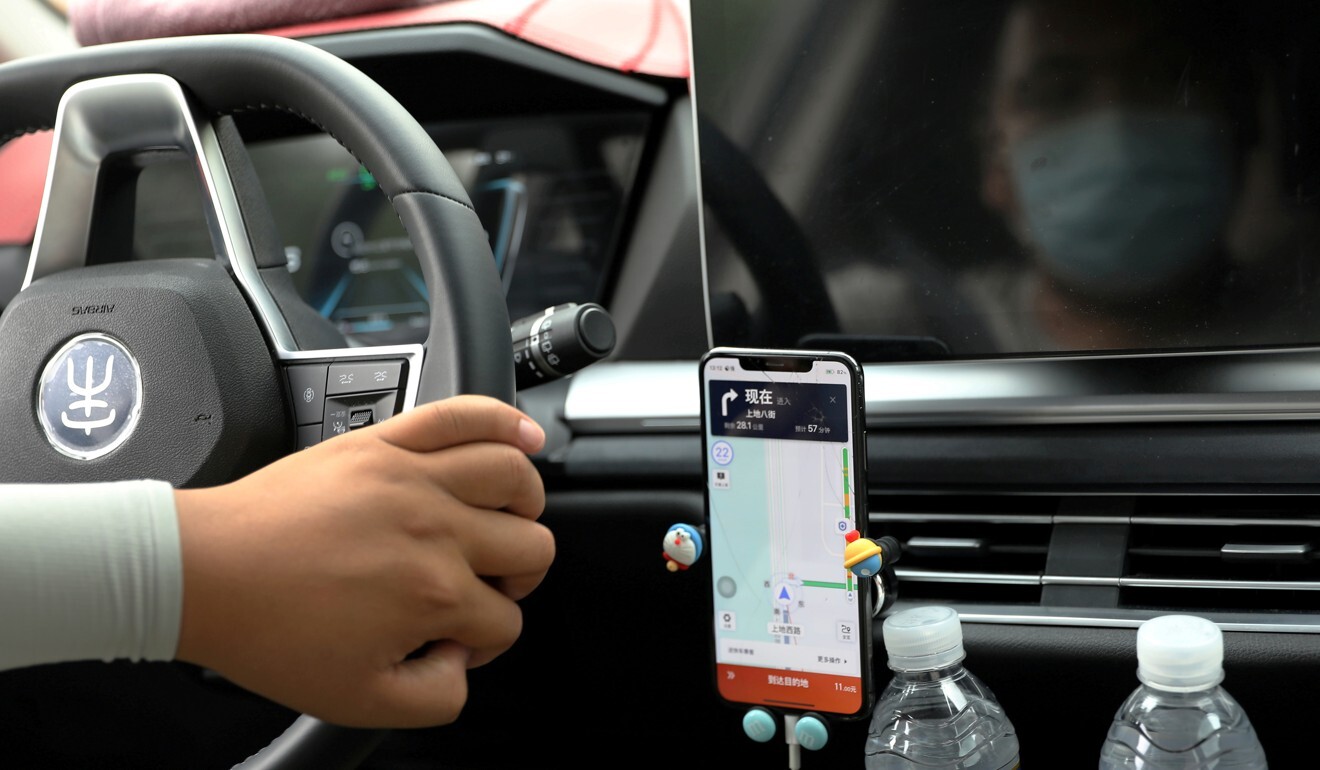 A driver of Chinese ride-hailing service Didi drives with a phone showing a navigation map on the platform’s app. Photo: Reuters