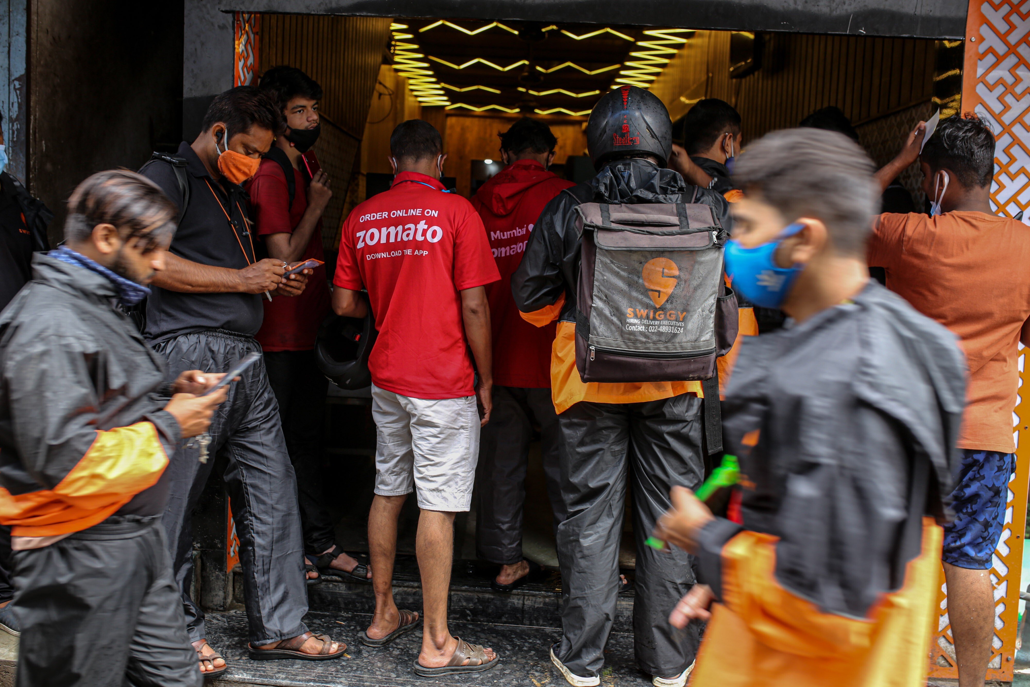 Delivery riders for Zomato and Swiggy, two Indian start-ups, wait to collect orders outside a restaurant in Mumbai. Photo: Bloomberg
