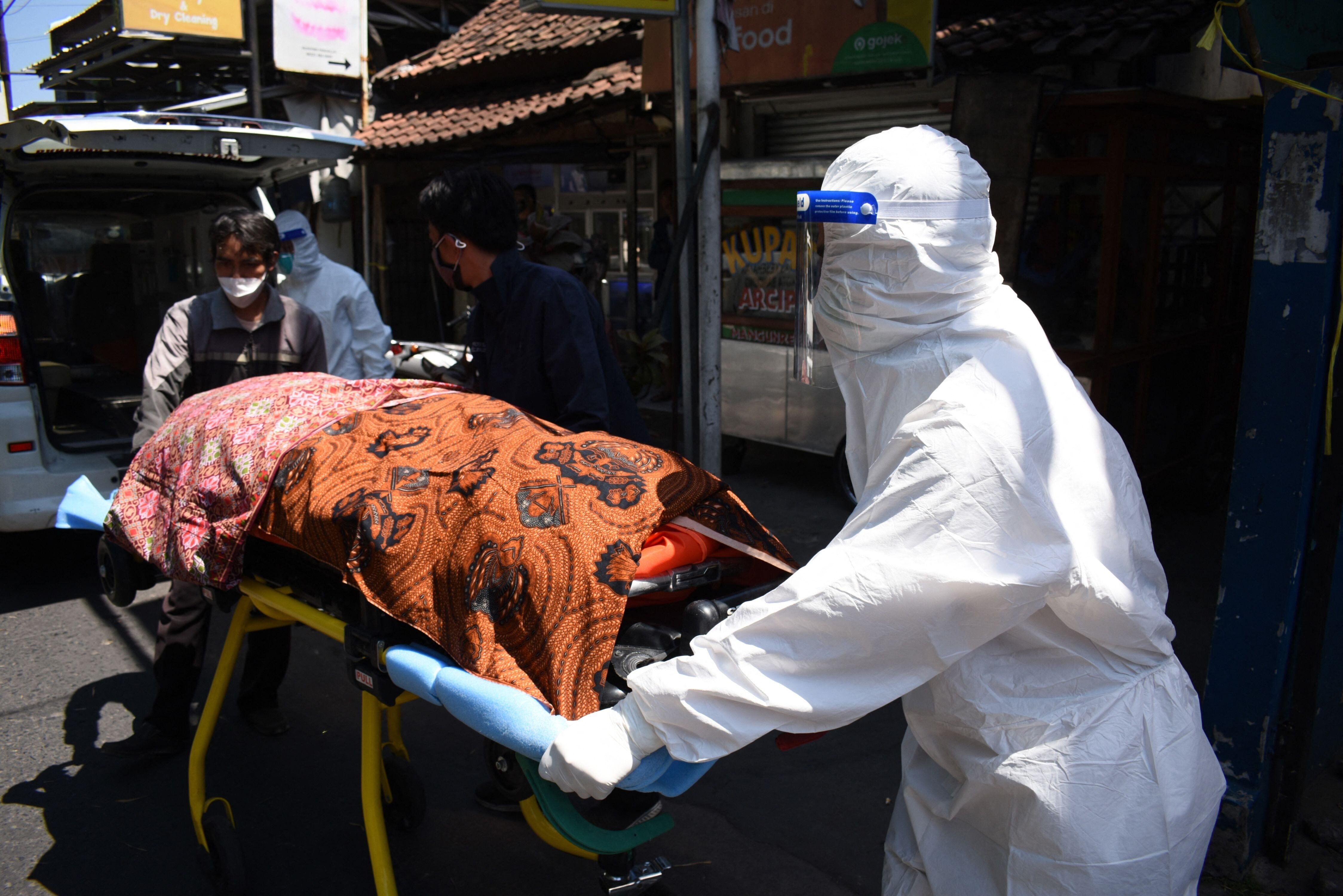 Health workers remove the body of a Covid-19 victim who died while isolating at home in Bandung, Indonesia. Photo: AFP