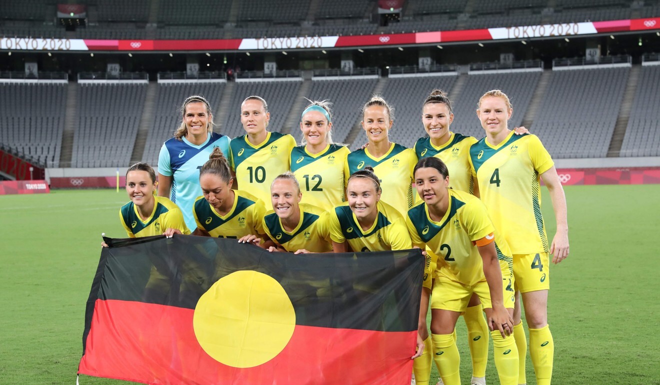 Australia’s Matildas football team pose with the Aboriginal flag before their match against New Zealand. Photo: AFP