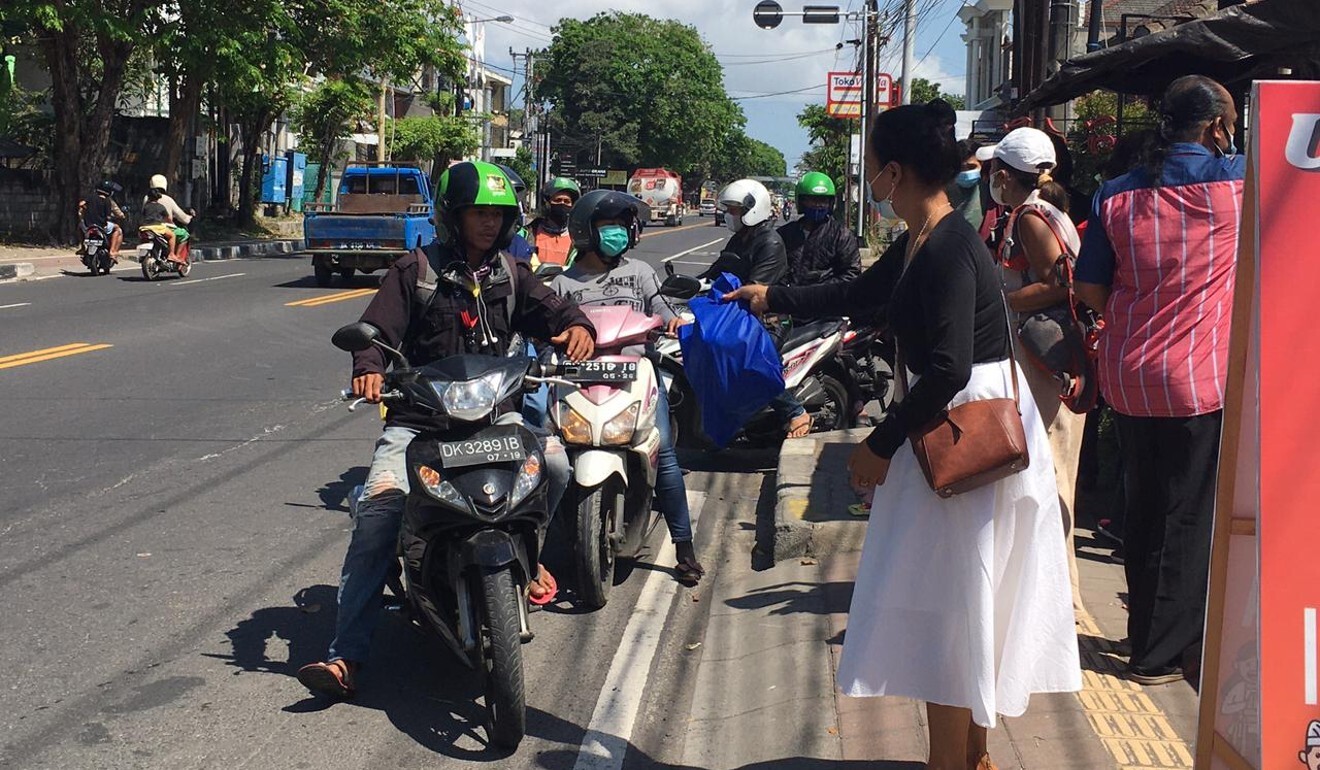 Passers-by in downtown Denpasar pick up food parcels. Photo: Luh Manis