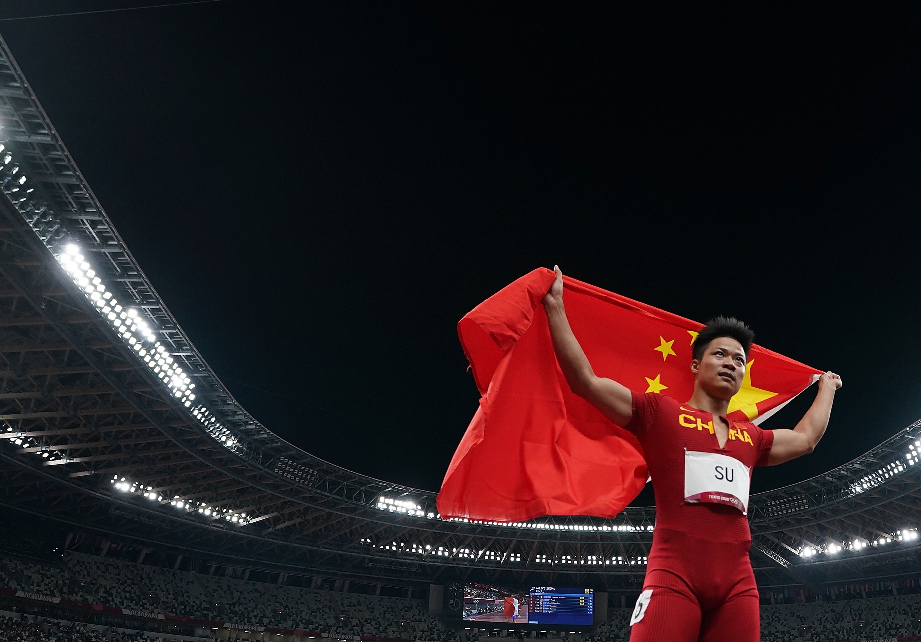 Su celebrates with the Chinese national flag after the men‘s 100m final at the Tokyo 2020 Olympic Games. Photo: Xinhua
