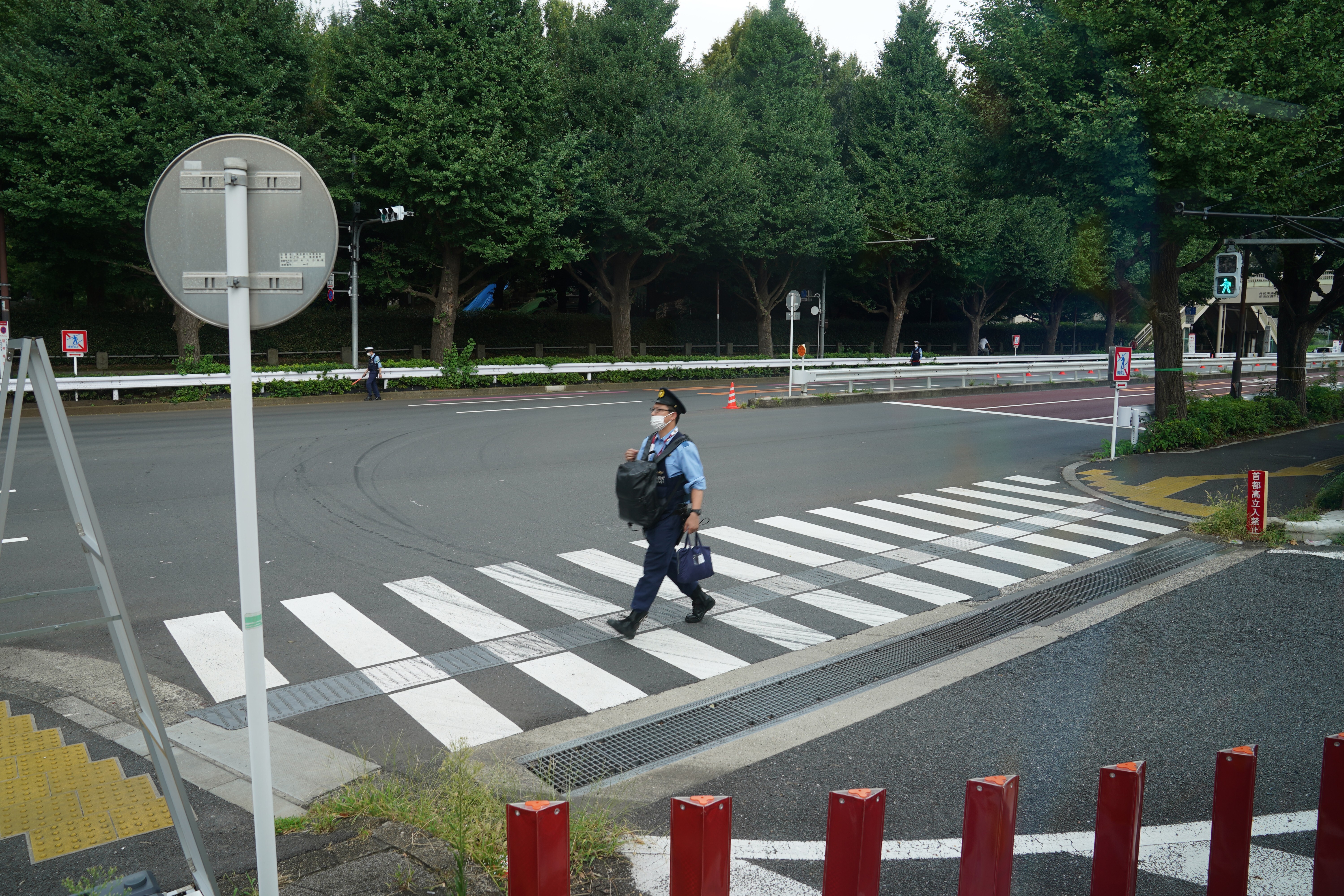 A Japanese police officer walks across a road outside the Olympic Stadium in Tokyo. A group of officers from Yamanashi have been relieved of their duties during the Paralympics for bad behaviour. Photo: DPA