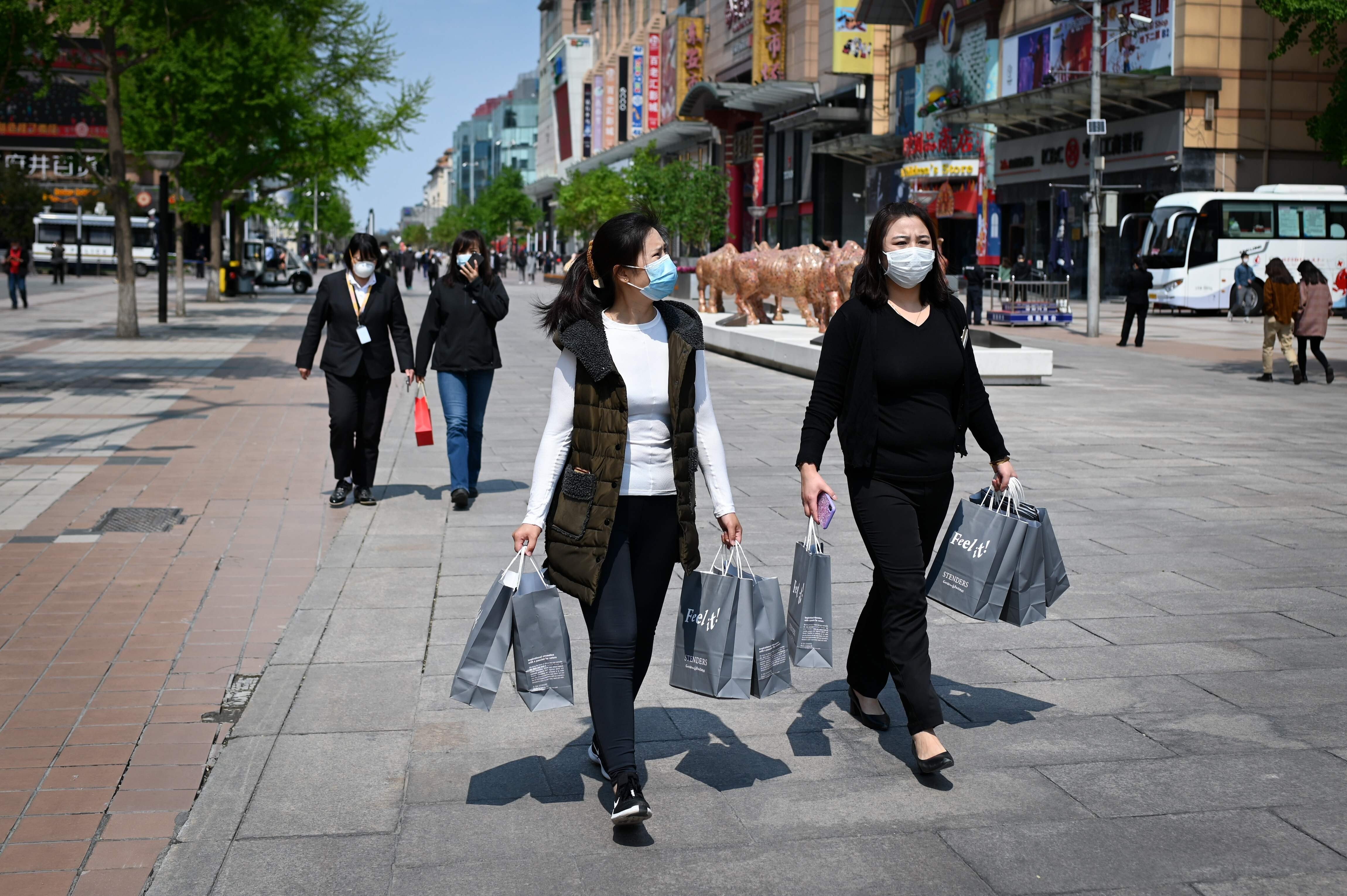 Two women walk along a business street in Beijing after shopping. Photo: AFP