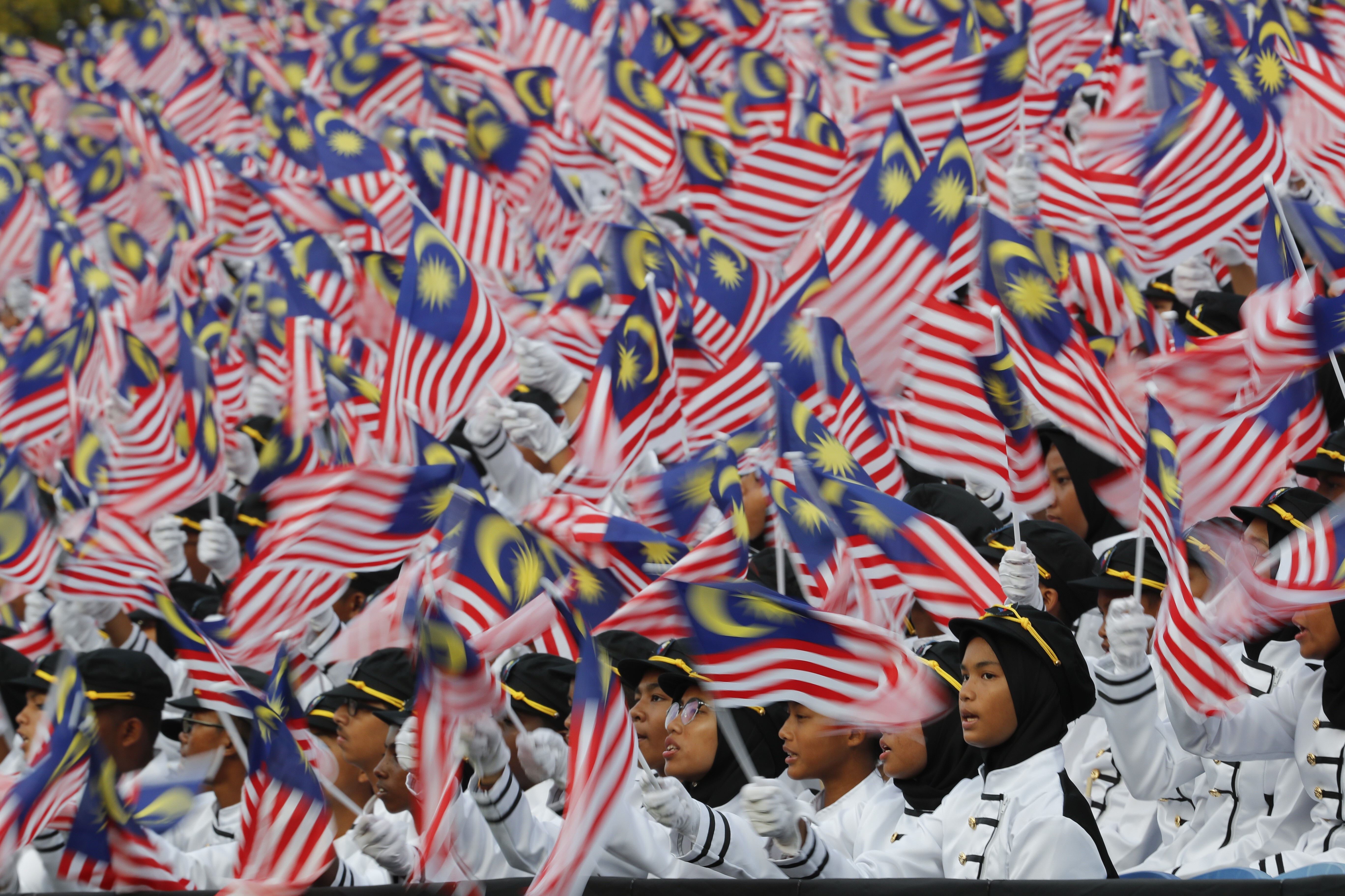Students wave national flags during Independence Day celebrations in Malaysia. Photo: AP