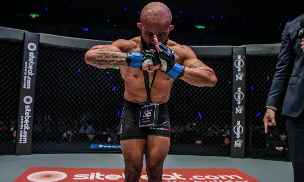 Demetrious Johnson bows in celebration after victory on his ONE Championship debut. Photos: ONE Championship