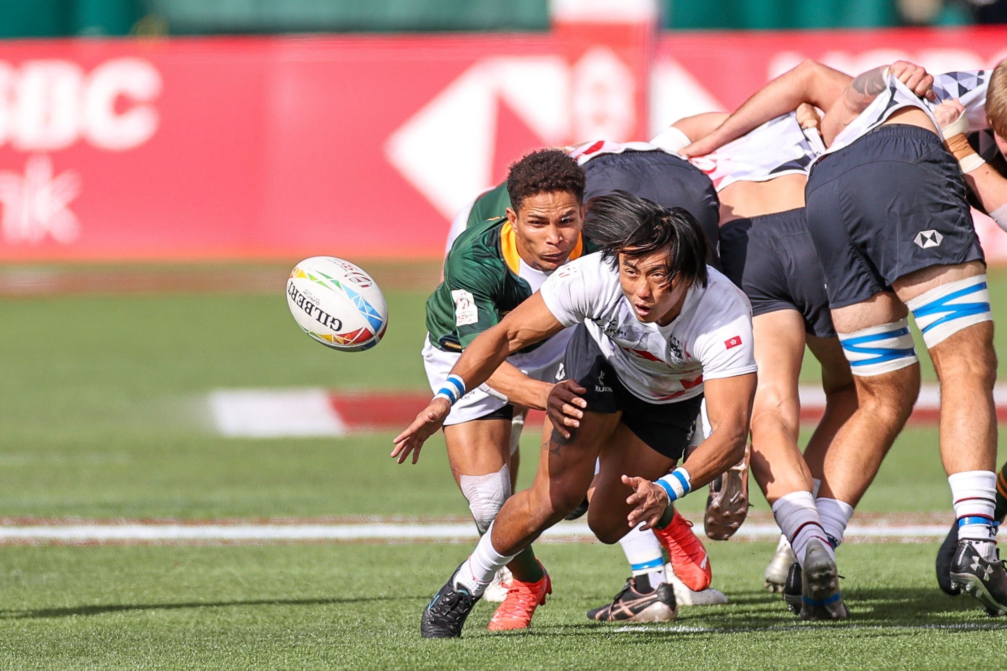 Hong Kong’s Cado Lee Ka-to passes the ball under pressure from South Africa during day one pool play. Photos: HKRU