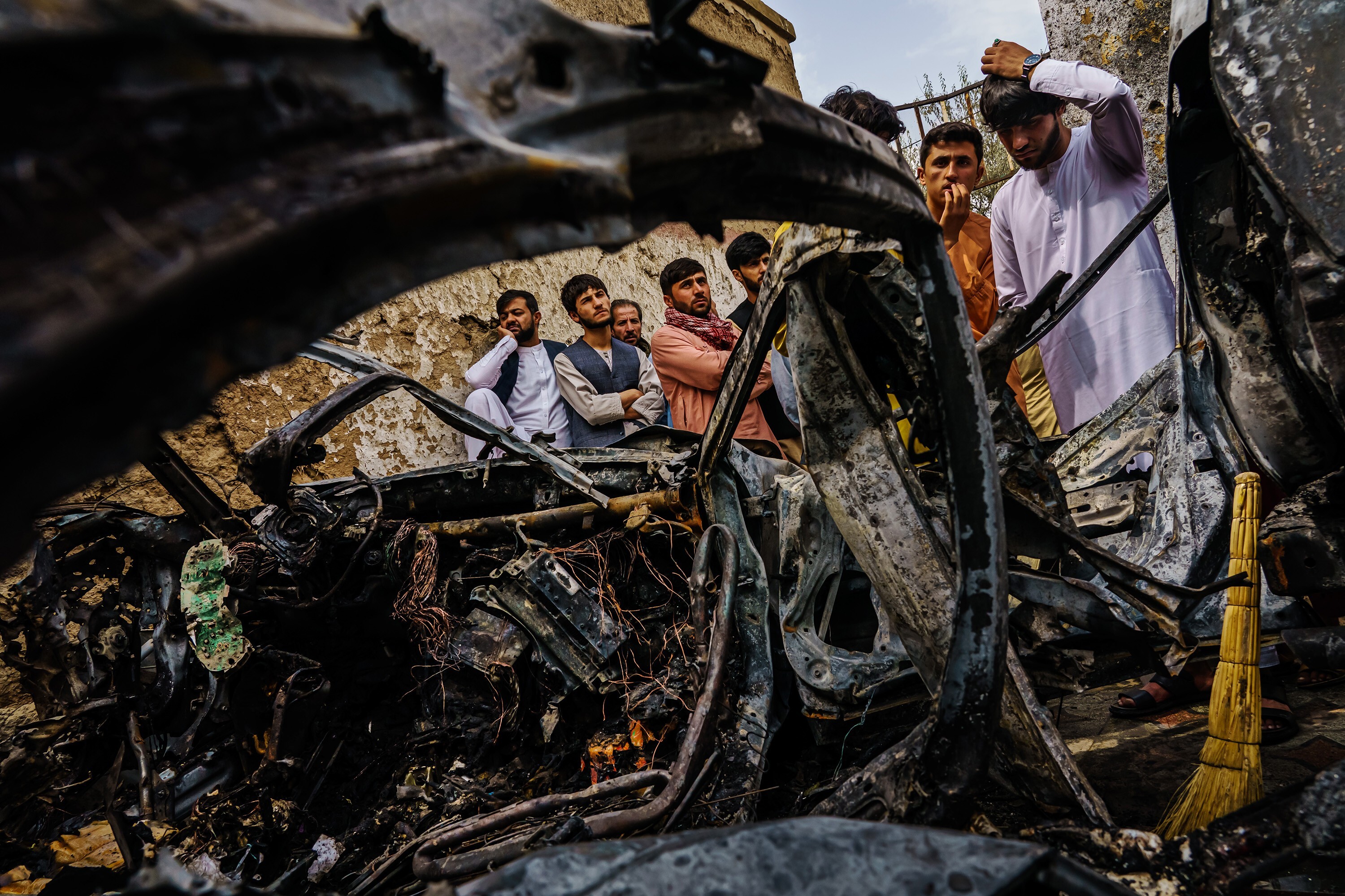 Relatives and neighbours of the Ahmadi family gather around the incinerated husk of a vehicle that was hit by a US drone strike in Kabul, Afghanistan. Photo: LA Times
