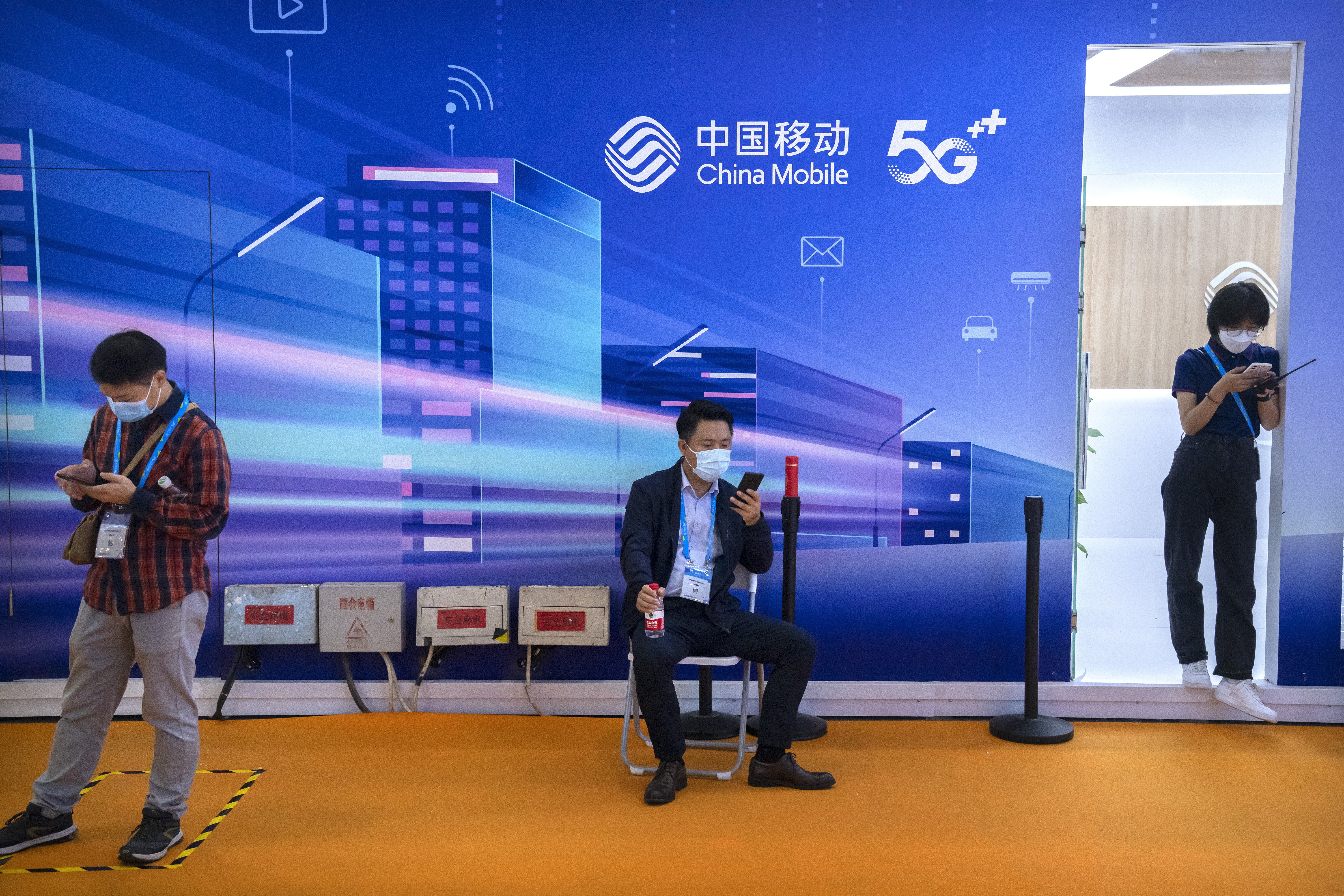 Attendees use their smartphones near China Mobile’s booth at the China International Information and Communication Exhibition, an annual event known as PT Expo China, in Beijing on September 28, 2021. Photo: AP
